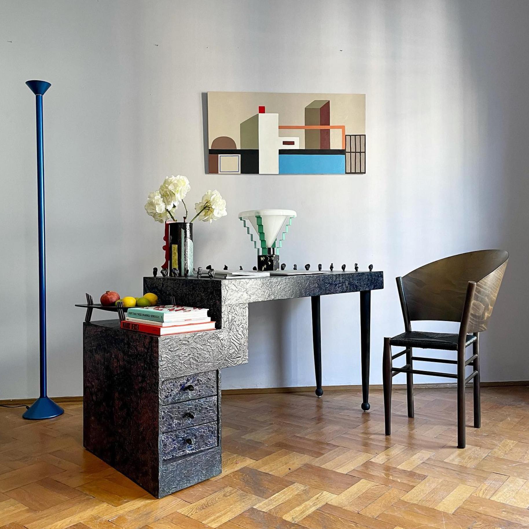 The writing desk was designed by Bohuslav Horák for Anthologie Quartett in 1990. It is a unique piece, made from wood and covered in hand-painted laminate, made as a tribute to Jackson Pollock. The desk features sculptural metallic elements in