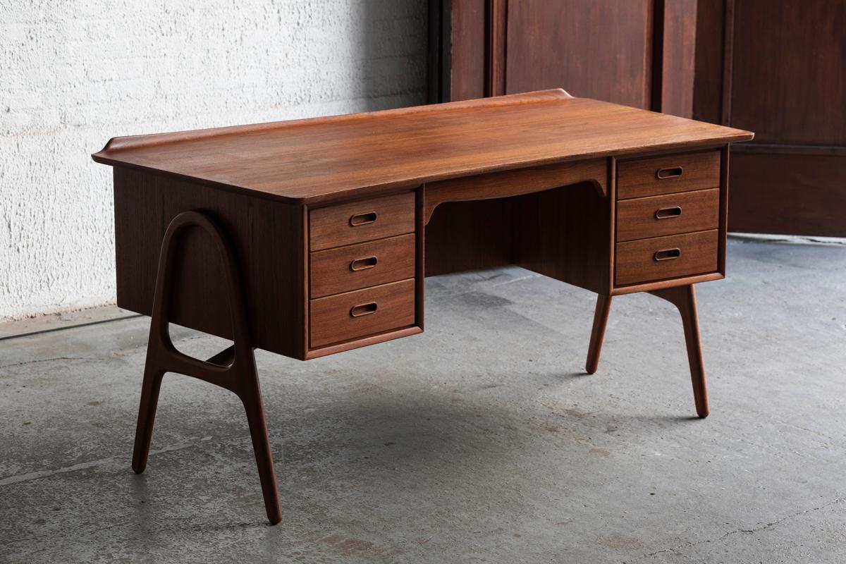 Freestanding writing desk designed by Svend Aage Madsen and produced by HP Hansen in Denmark around 1960. Beautiful shaped desk with a solid teak wooden frame and 3 drawers on each side of the desk. The boomerang shape contains a shelf for books on