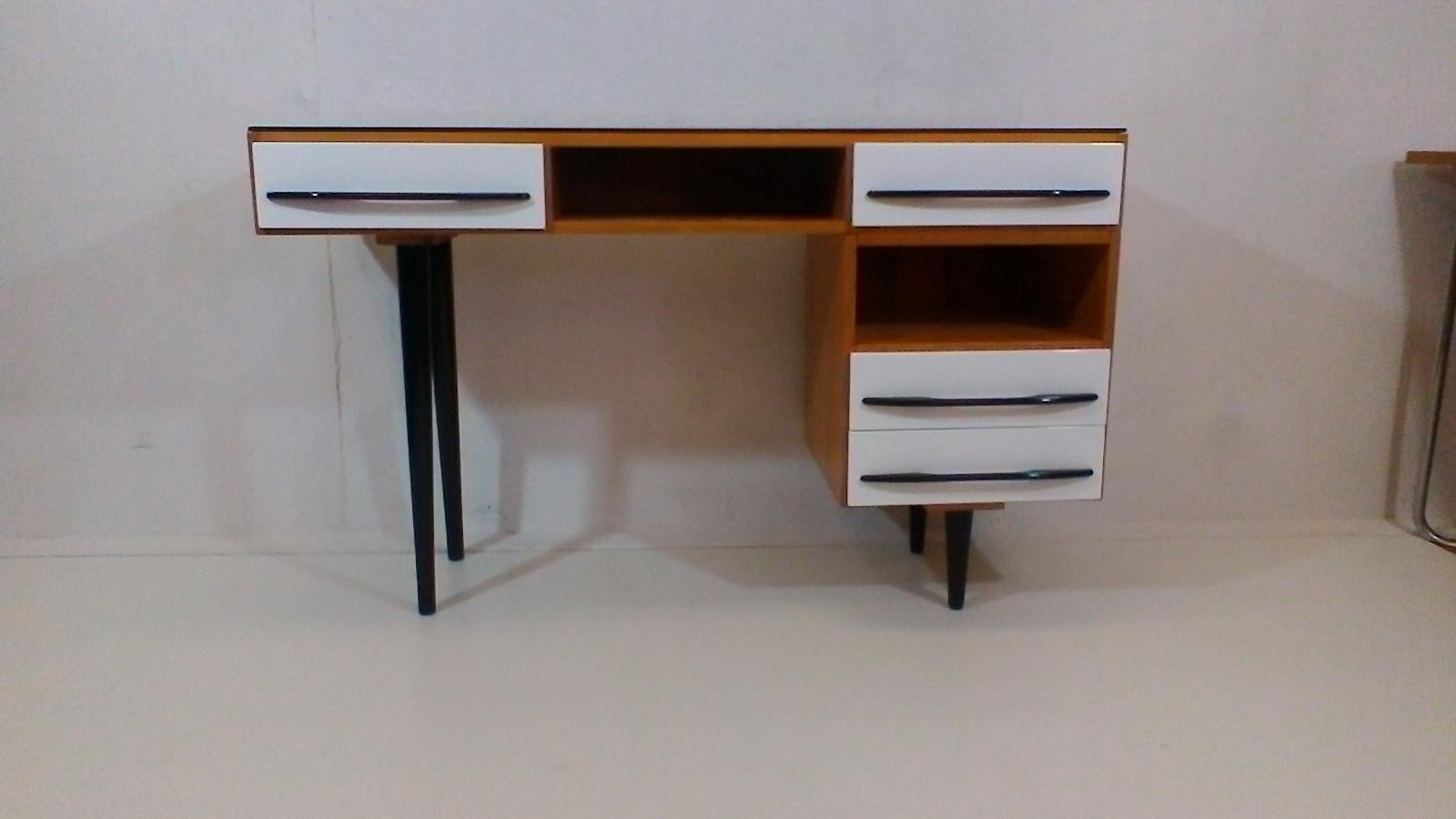 The item is made of veneered and varnished wood, on upper surface is black opax glass, corpus is varnished quality polyurethane varnish. drawers and legs are varnished into the original colours- black and white in high gloss.