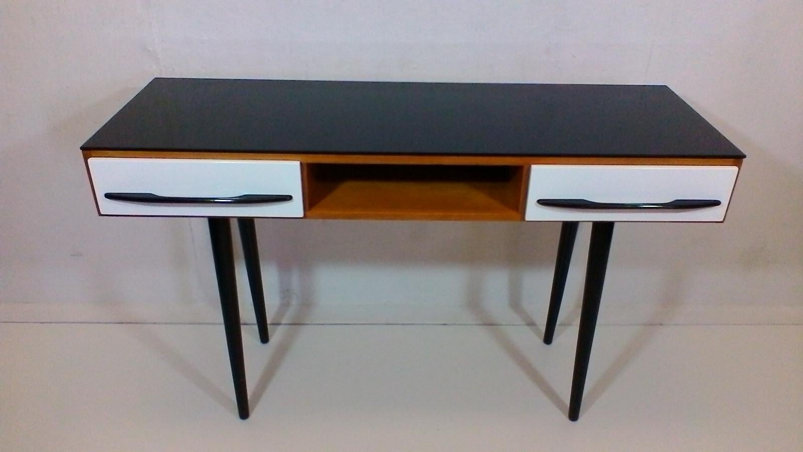 Czechoslovakia. The item is made of veneered and varnished wood, on upper surface is black opax glass, corpus is varnished quality polyurethane varnish. Drawers and legs are varnished into the original colors- black and white in high gloss. Complete