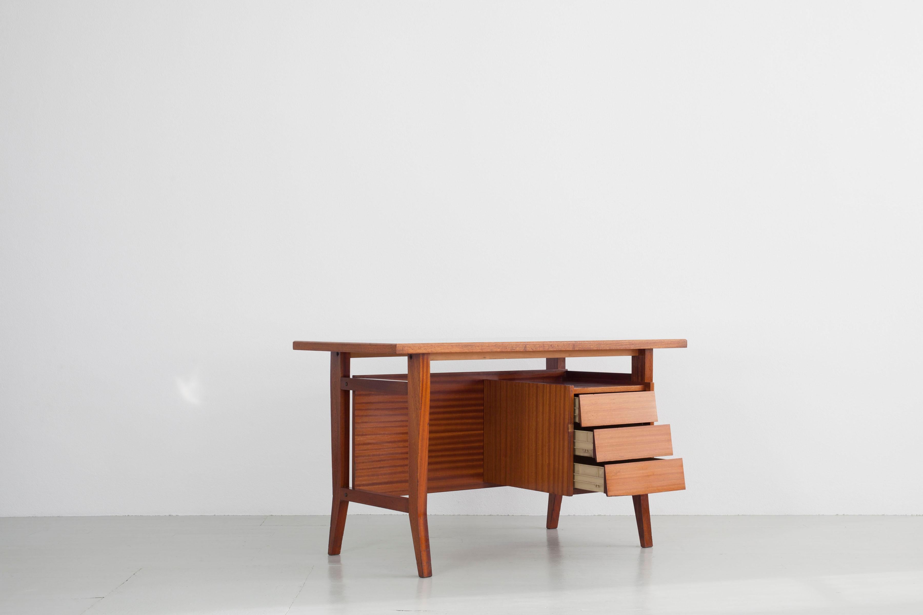 Desk design: Gio Ponti, Manufacturer: Scirolli, Italy, 1960s

This beautiful wooden desk of angular linear shapes is in original condition and has a drawer element. The inset gray-green laminate top has light scratches, and a small veneer repair has