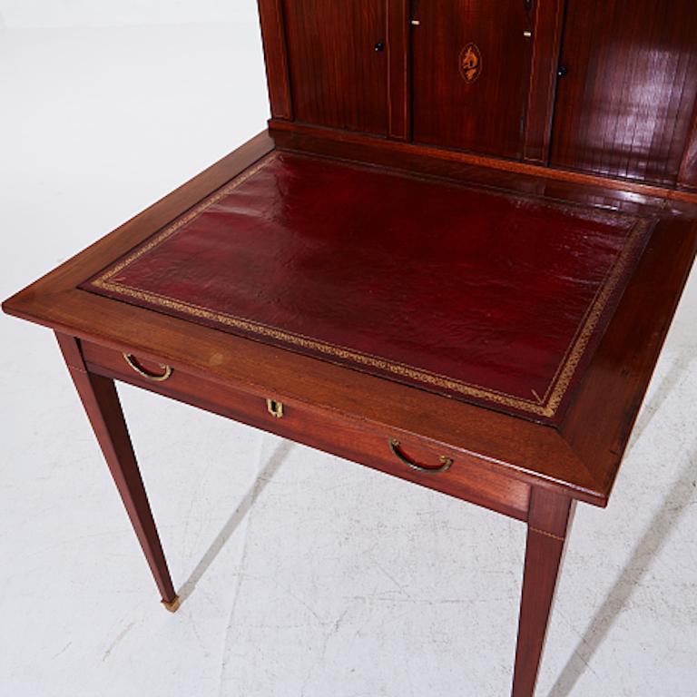 A writing desk with a drawer and shelving. On the surface is a red leather writing board. The foot legs of the desk have lovely brass ends. Desk is from the early 19th Century mahogany. 
Beautiful and unique. If interested i will send you additional