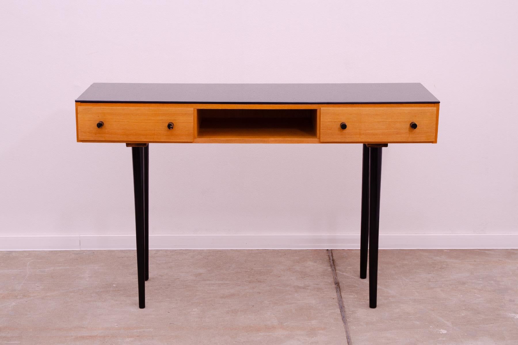 This Midcentury piece was made in the former Czechoslovakia in the 1960´s. It was designed by the famous architect Mojmír Požár for UP Závody. It´s made of beech wood, ash wood and has a black glass on the top.

It´s in very good Vintage condition,
