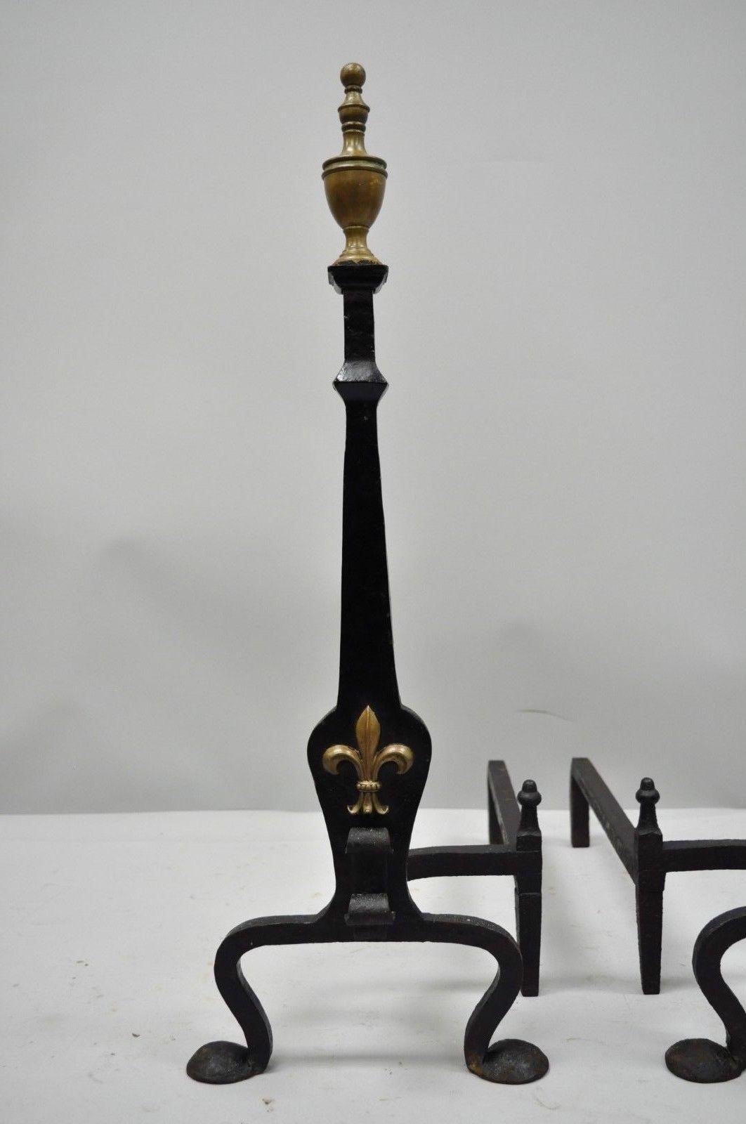 Pair of antique wrought and forged iron brass urn finial gothic revival fireplace Andirons. Item details solid brass urn finials and brass fleu de lis ormolu, forged wrought iron construction, and shapely cabriole legs, circa 1900. Measurements: 31