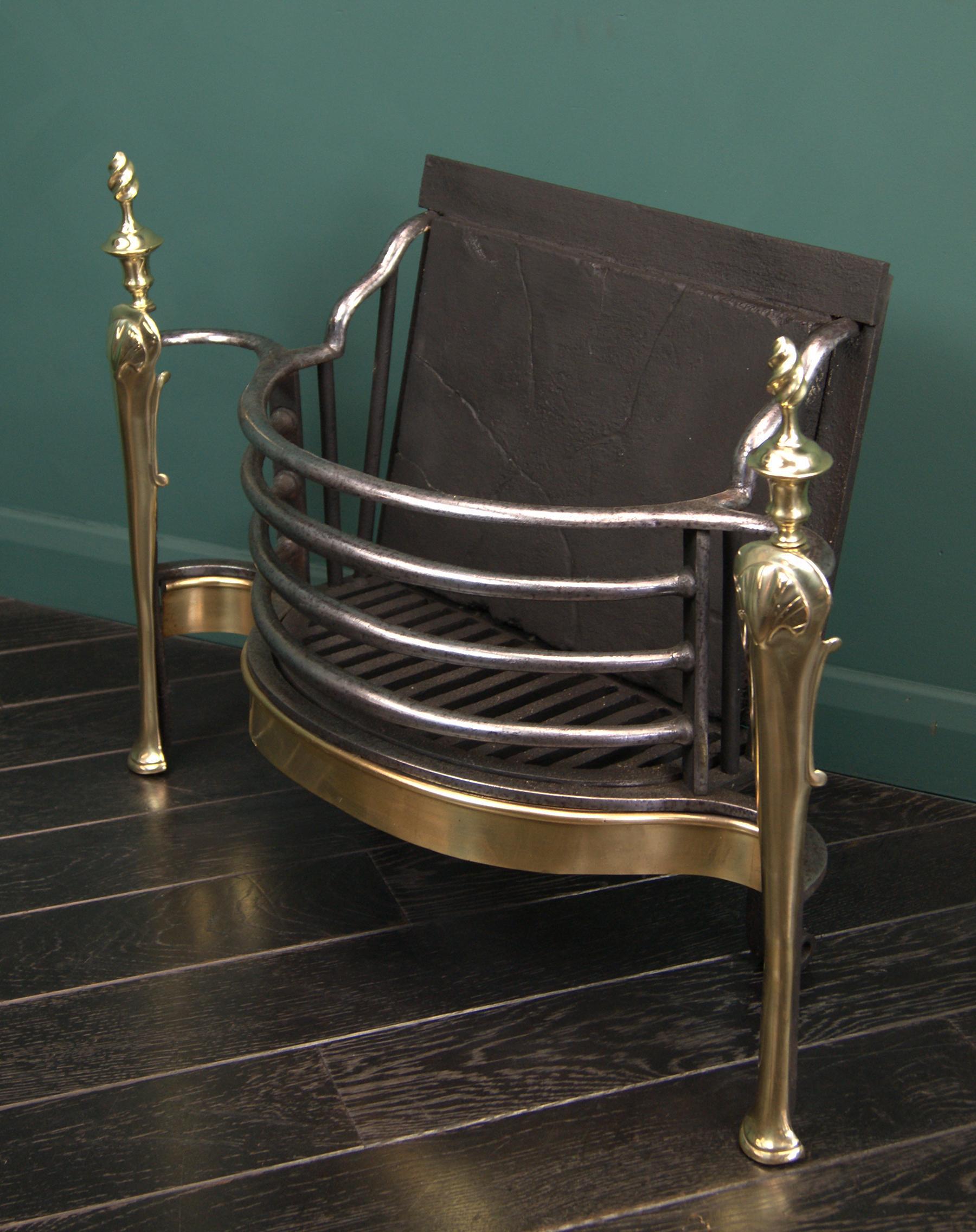 A fine 19th century English brass and wrought fire grate in the Queen Anne style. The delicately curved fire bars are set above a brass apron flanked by brass standard with flame finials uppermost. Restored. 
Circa 1890