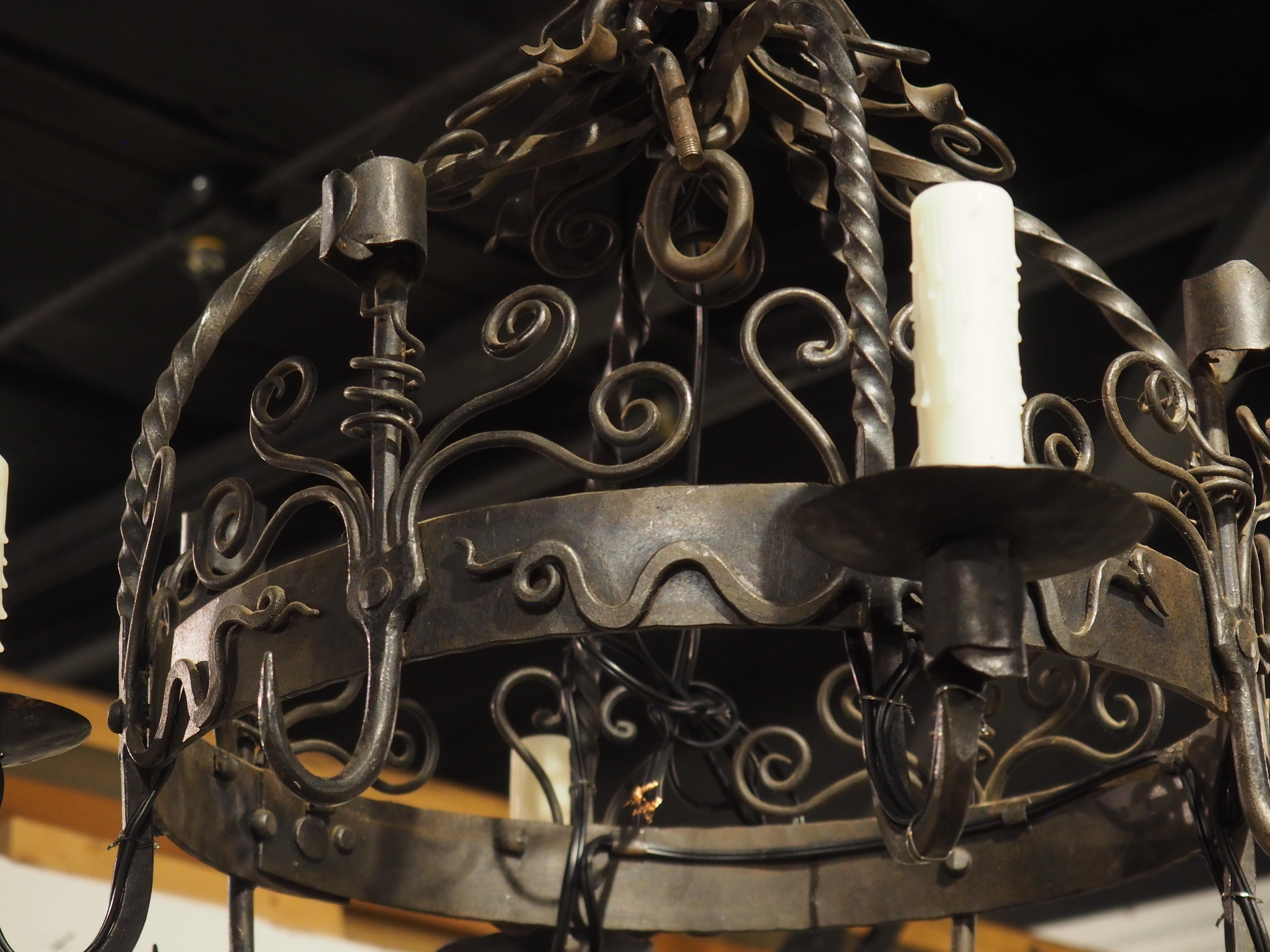 Ulteriori informazioni in arrivo...

I bracci contorti in ferro battuto di questo lampadario francese del 1900 sono abbinati a una serie di tralci di vite.  Tra i quattro bracci c'è un gancio per pentole di forma simile, che lo rende un'opzione