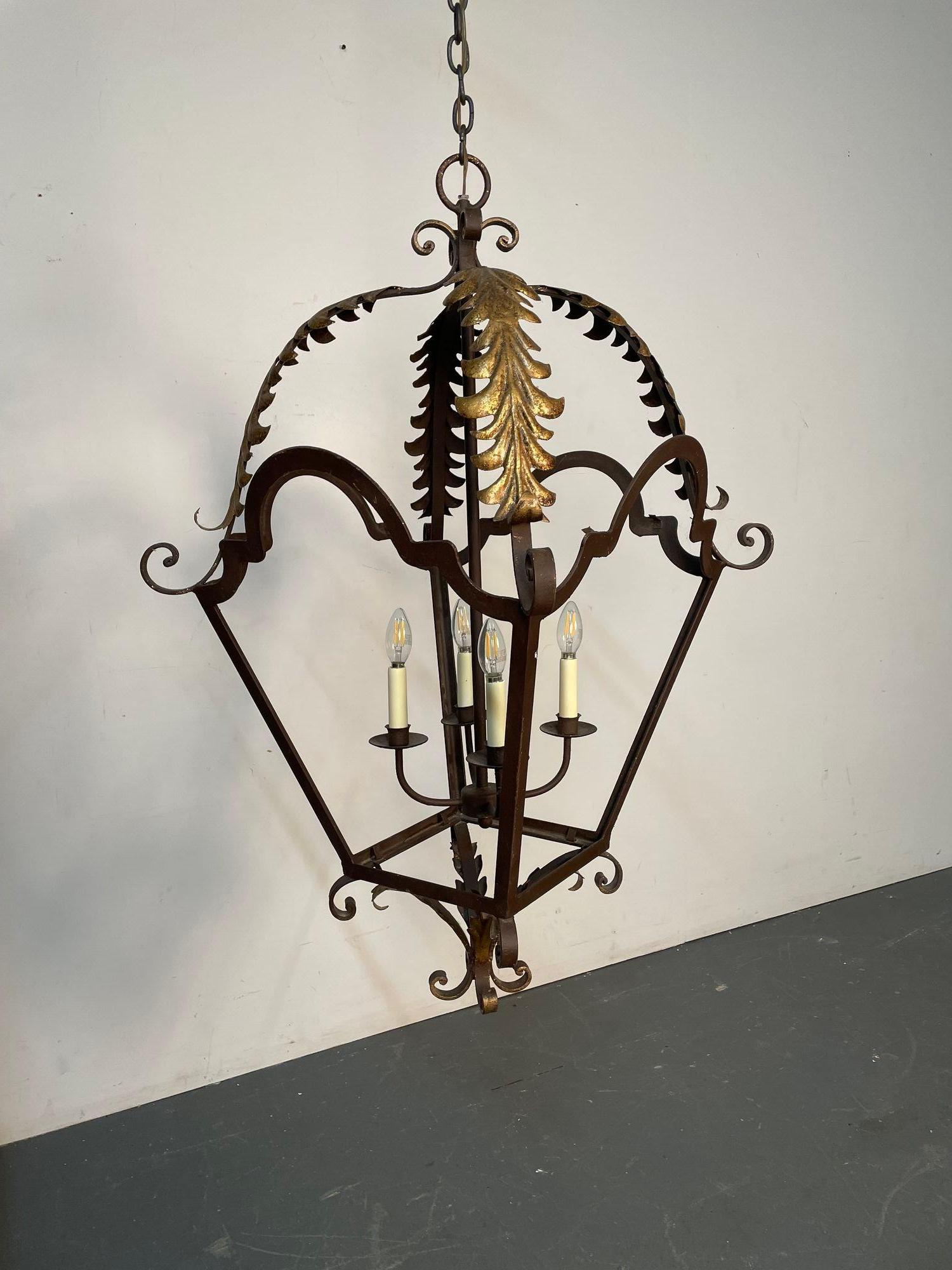 Wrought Iron and Brass Architectural Lantern Chandelier

Having a leaf and scroll form design with gilt metal or brass adornments. A large and impressive lantern having a long chain and matching canopy. The whole having an open design on all