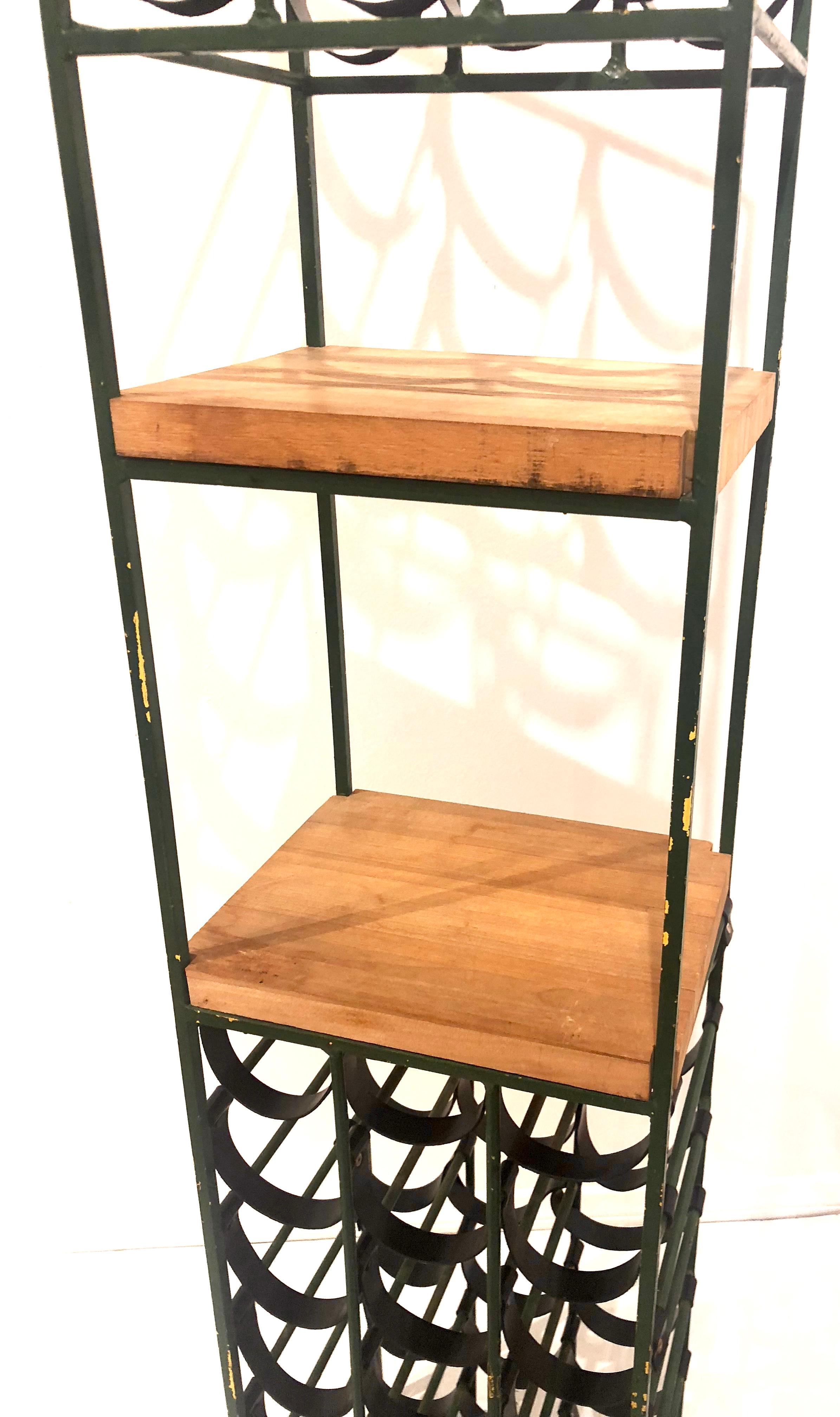Tower wine rack by Arthur Umanoff, made of wrought iron with new black leather straps, two butcher block shelves for cutting or display, holds 30 bottles each. It has its original painted finish its distressed look in a green yellow finish, we