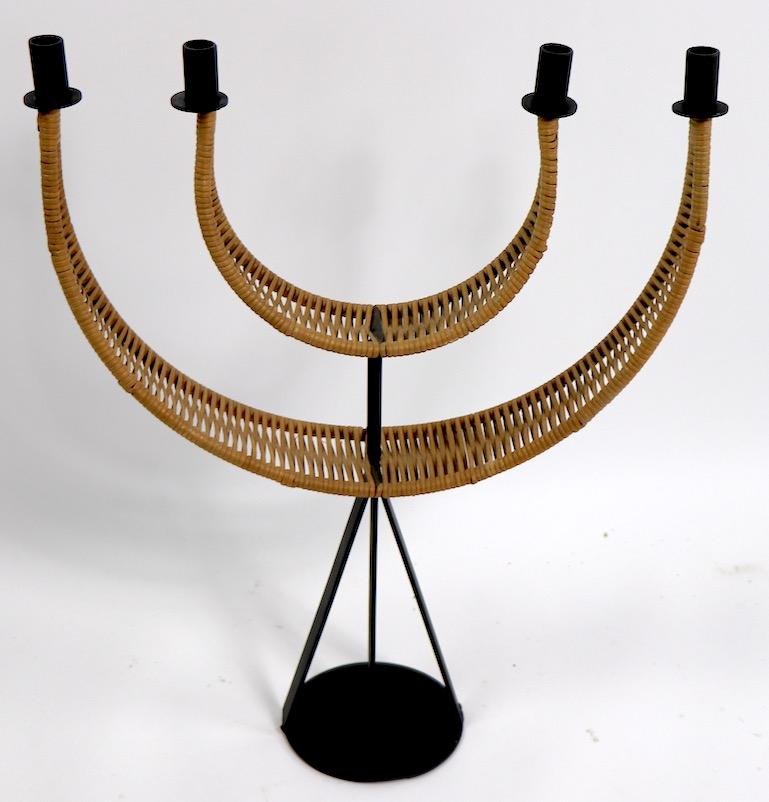 Architectural candelabrum designed by Arthur Umanoff, constructed of wrought iron and cane woven wicker, having four candle cups on two arch form arms. Very stylish item in clean and ready to use condition.