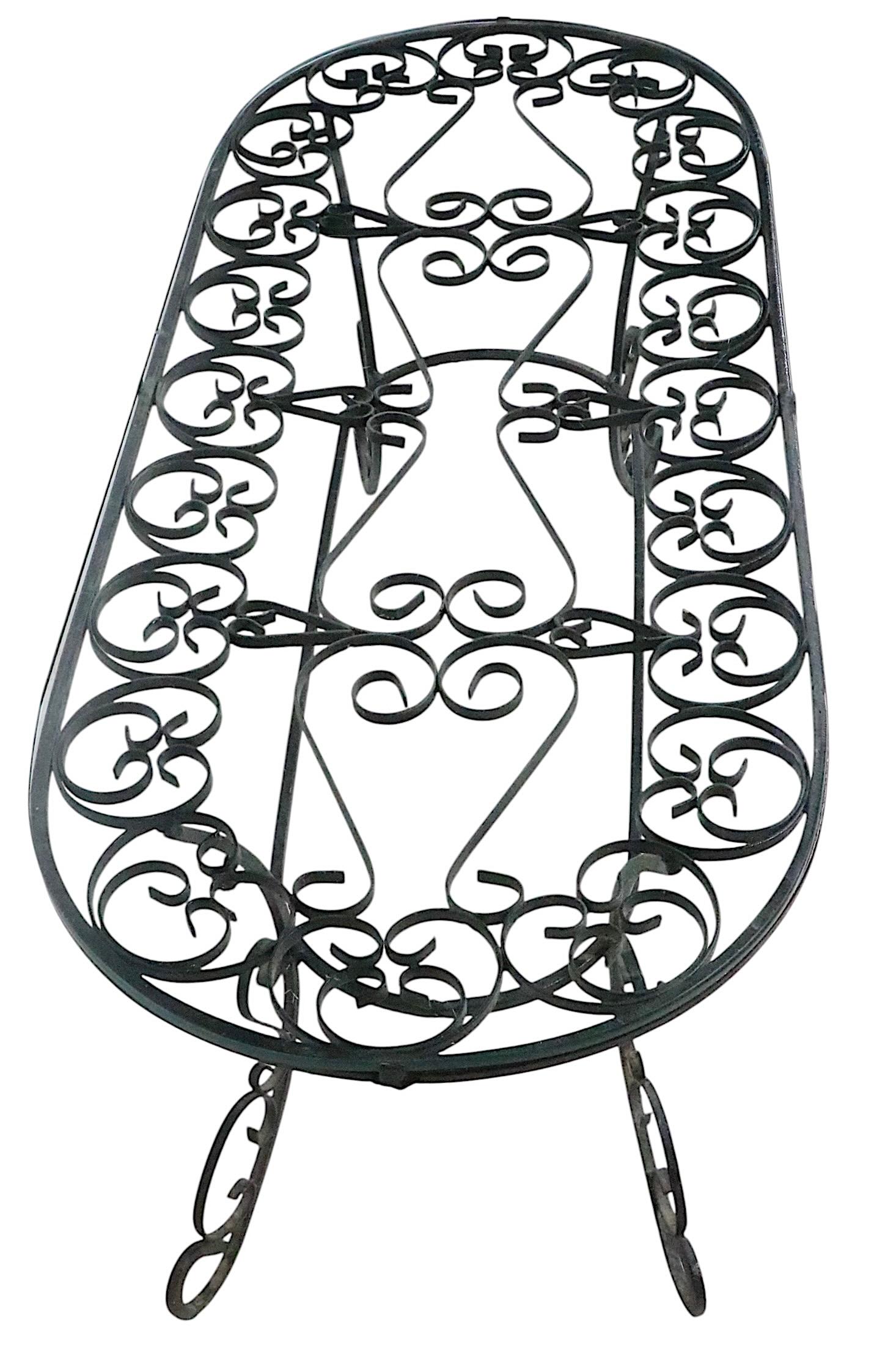 Élégante table basse en fer forgé et verre, avec une base en métal ouvragé et un plateau en verre trempé. Ce site  Cette table convient aussi bien à l'intérieur qu'à l'extérieur, et est parfaite pour un jardin, un patio ou une véranda. Circa