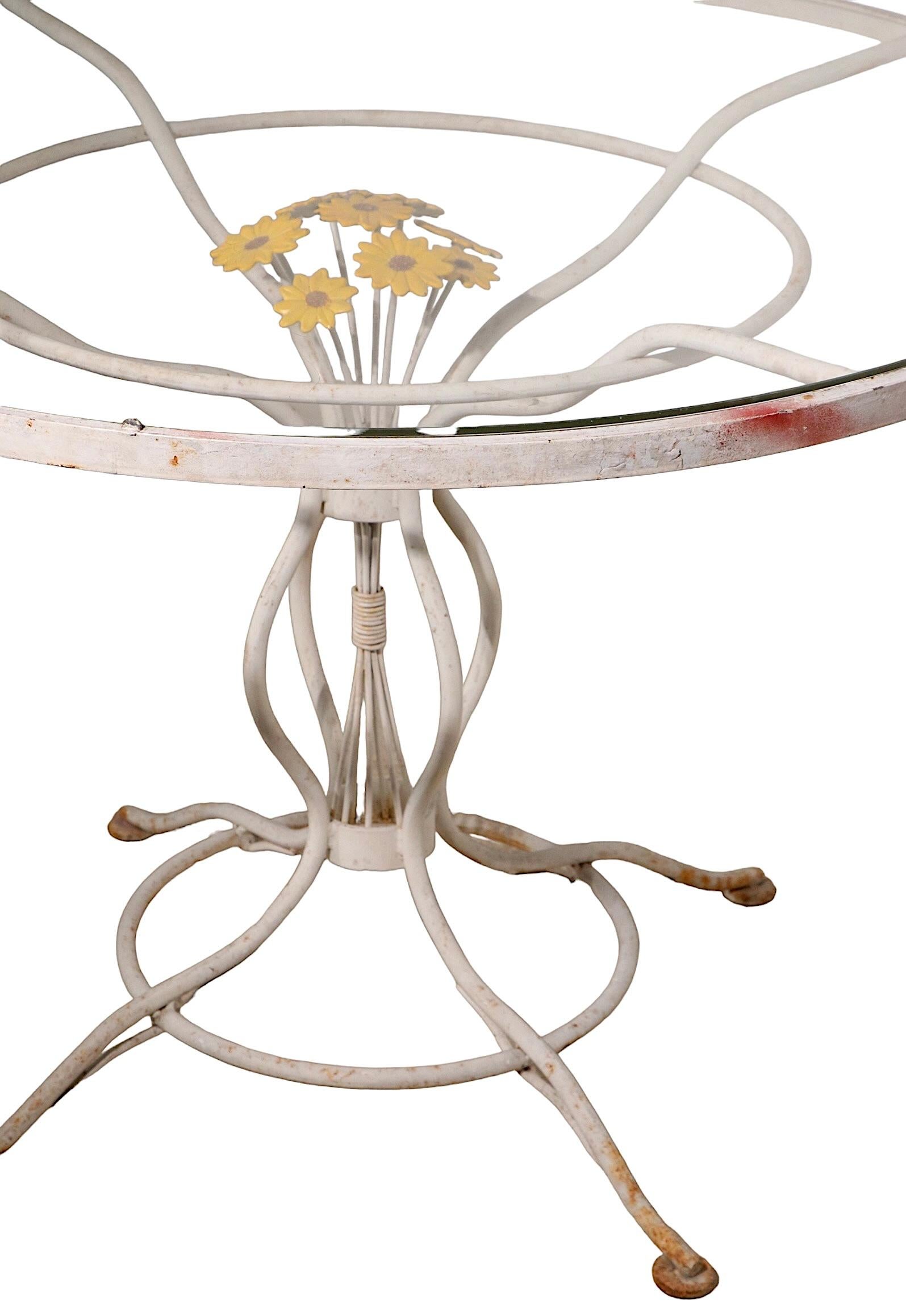 Unusual wrought iron dining, cafe table with glass top. This fun table features a cast metal bouquet of flowers, making it the perfect garden, patio, sunroom or poolside table. The table is in very good original condition, showing only light