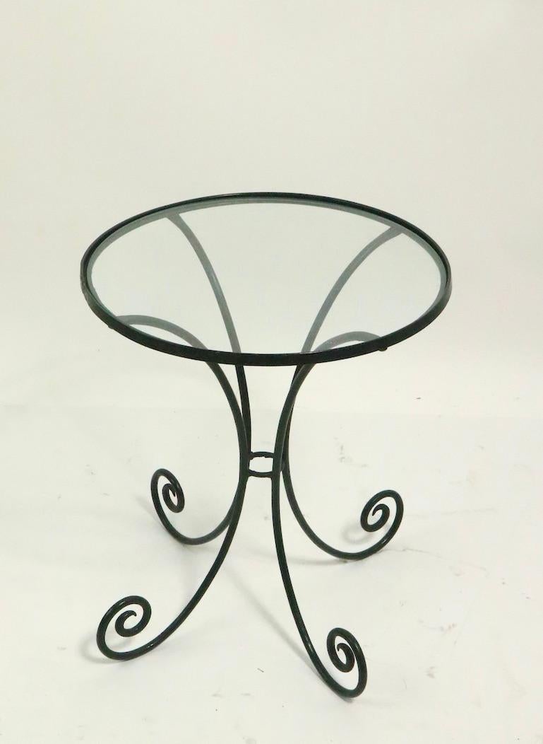 Sweet Art Deco side table having a wrought iron structure and original circular plate glass top. Clean, ready to use condition, currently in later dark green paint finish.
Suitable for indoor and outdoor use, attributed to Salterini.
