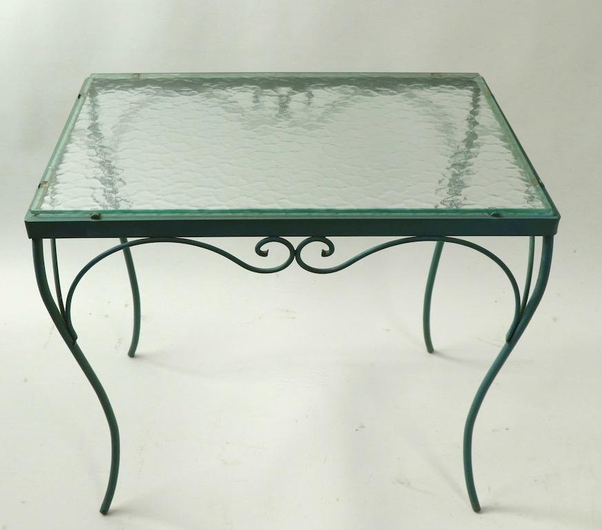 Stylish and chic wrought iron table with original textured glass top. Original blueish green paint finish, clean and ready to use condition. Originally designed for outdoor use, but also suitable for indoor, or patio use as well. Please view the