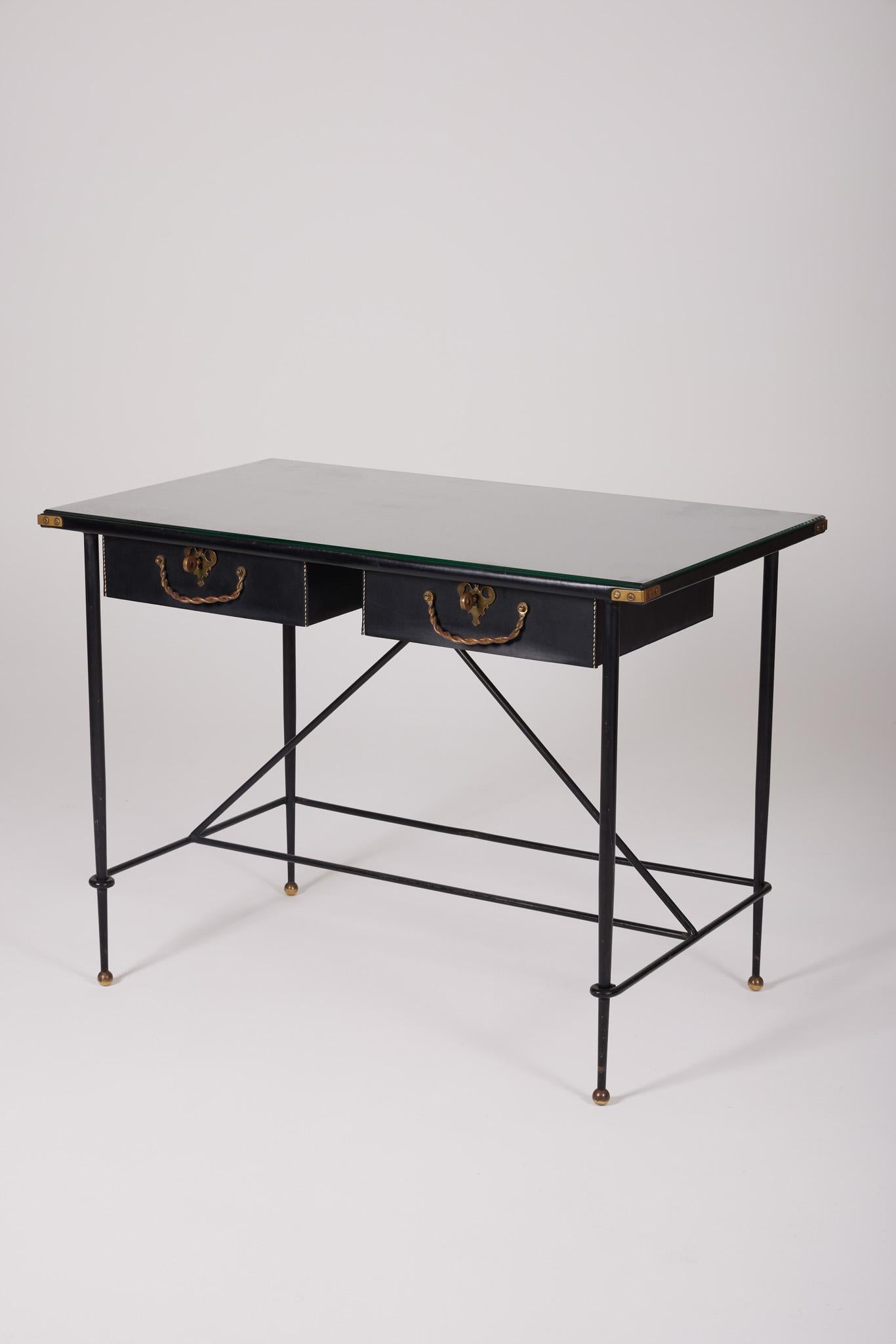 Exceptionnel bureau du designer Jacques Adnet (1900-1984), années 1940. La base est en fer forgé patiné noir, le plateau est en verre et les détails du bureau sont en cuir et en laiton. Les deux tiroirs coulissants sont recouverts de cuir cousu à la