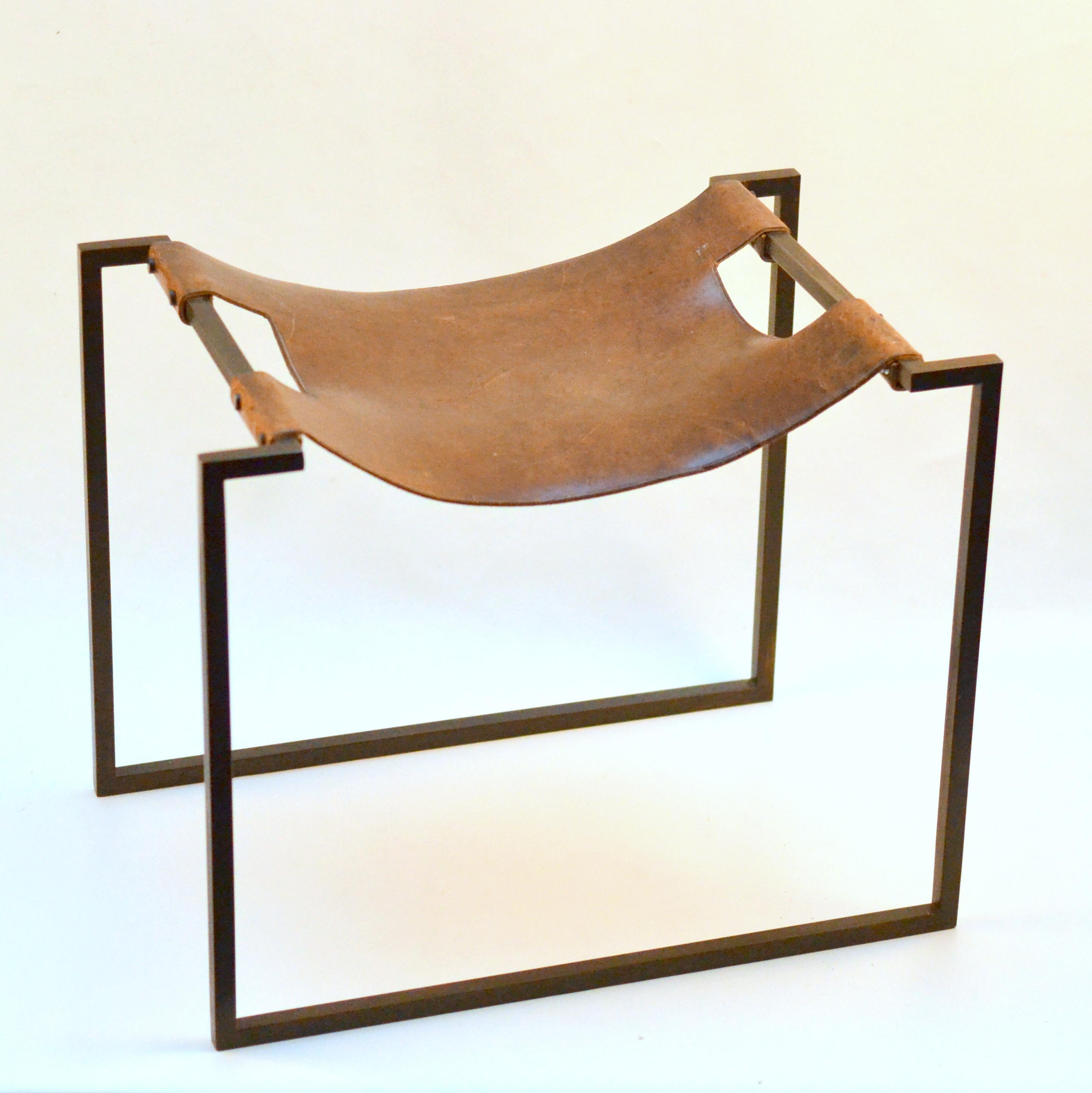 Hand forged stool was probably produced in the 1960's, where its construction was fabricated by cleverly using right angled iron bar for strength and minimal design. The hide leather loops over the ‘U’ shaped arms of the seat to form a sling and is
