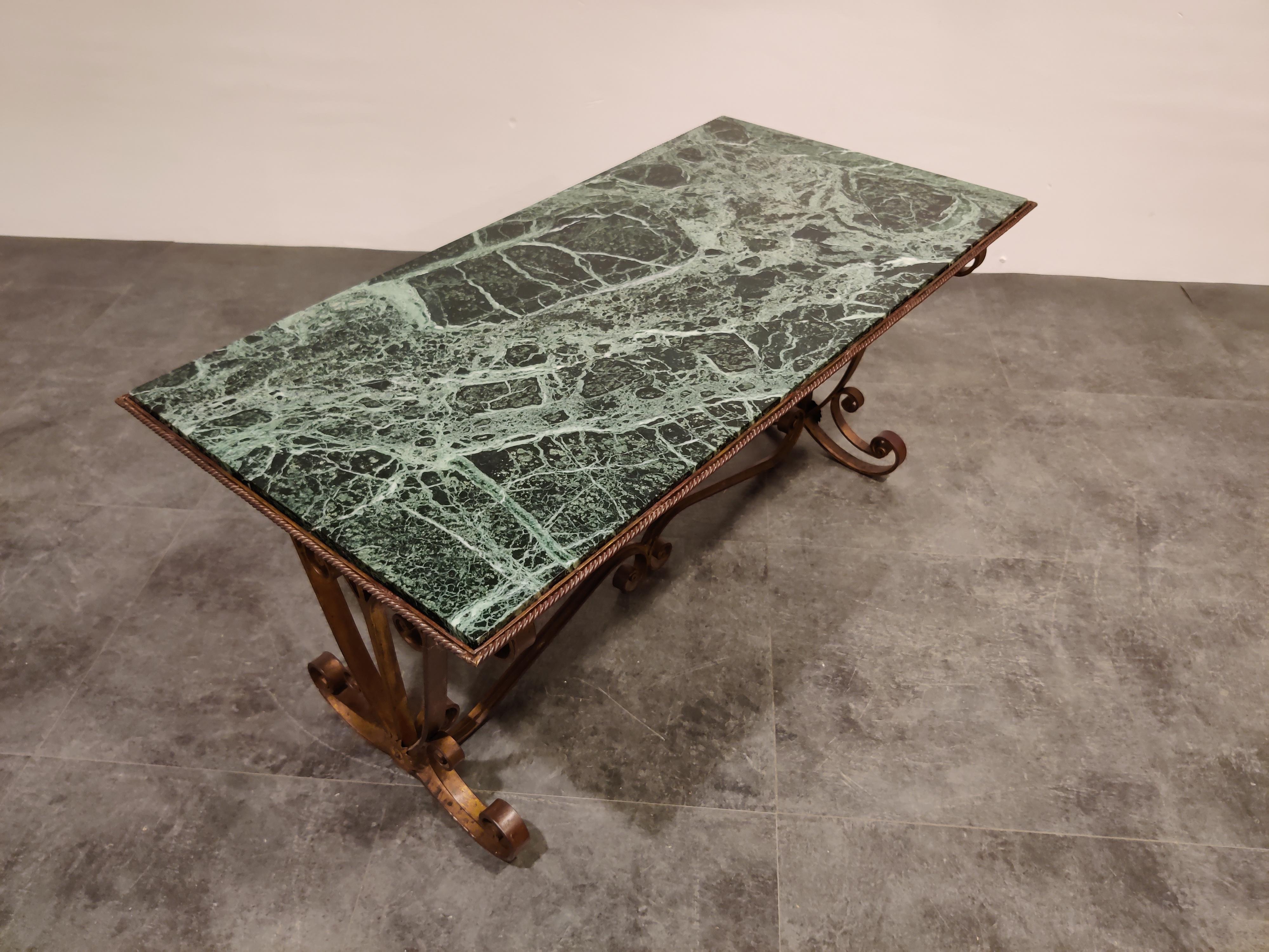 Exquisite midcentury wrought iron coffee table in the style of Raymond Subes.

Very well made with beautiful details and a perfect dark green vained marble top.

The combination of materials and craftsmanship creates this beautiful elegant