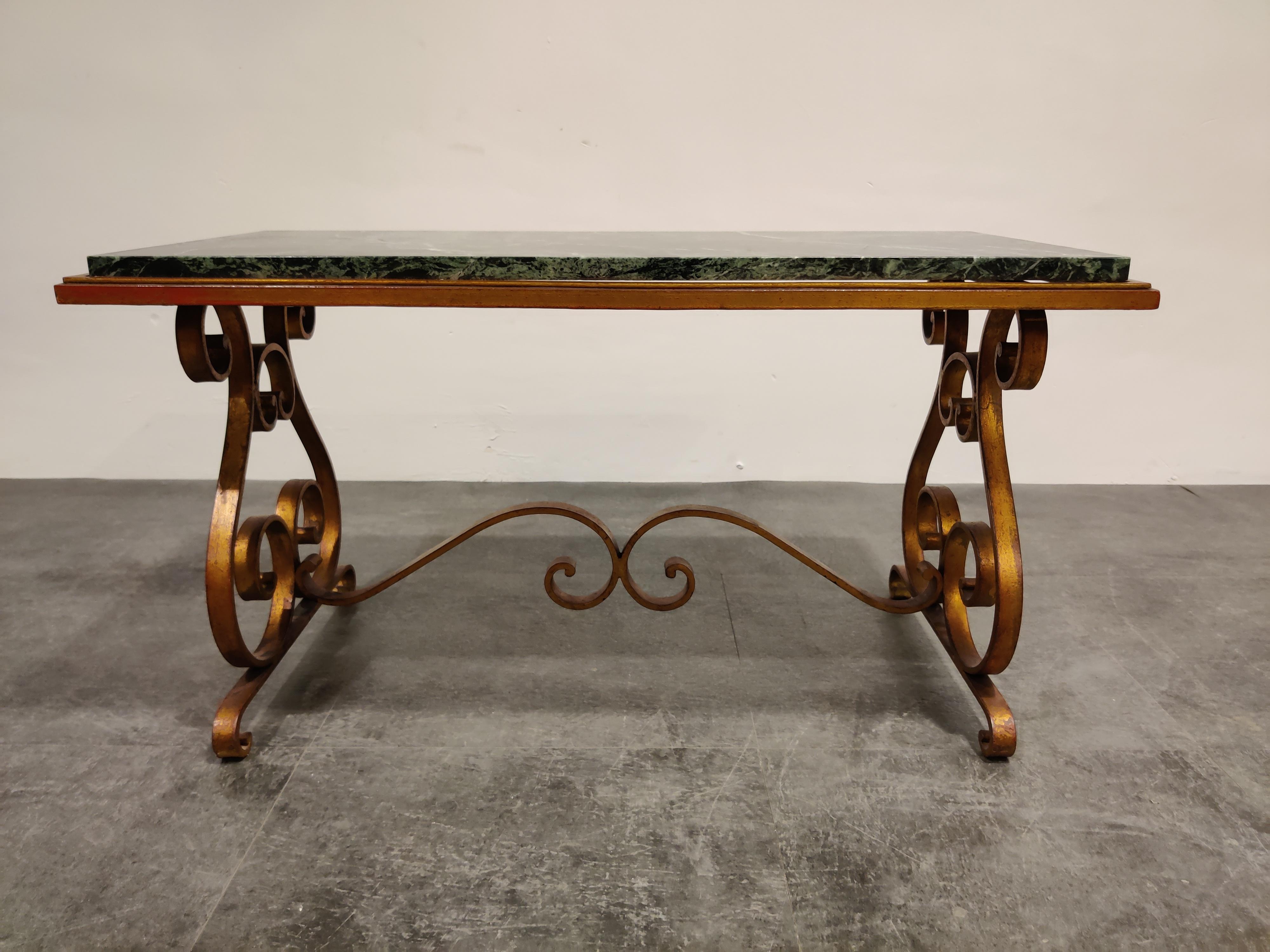 Beautiful midcentury wrought iron coffee table in the style of Raymond Subes.

Very well made gilded frame with a perfect dark green veined marble top.

The combination of materials and craftsmanship creates this beautiful elegant coffee