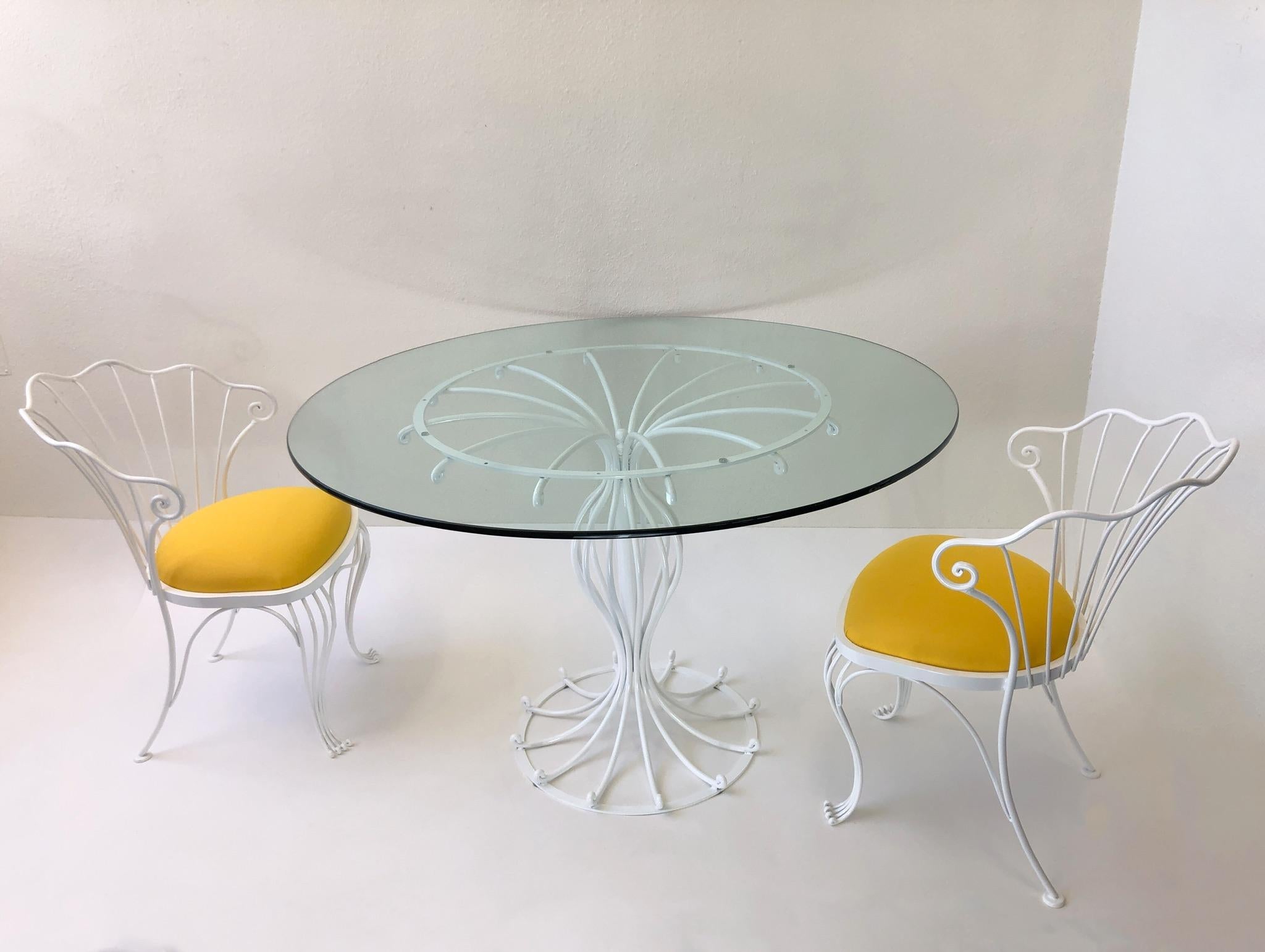 A glamorous powder coated white wrought iron and yellow sunbrella patio set designed by Russell Woodard in the 1970s. The set has been newly powder coated, seats recovered in a yellow sunbrella fabric and a new 1/2 inch thick 48” diameter glass top.