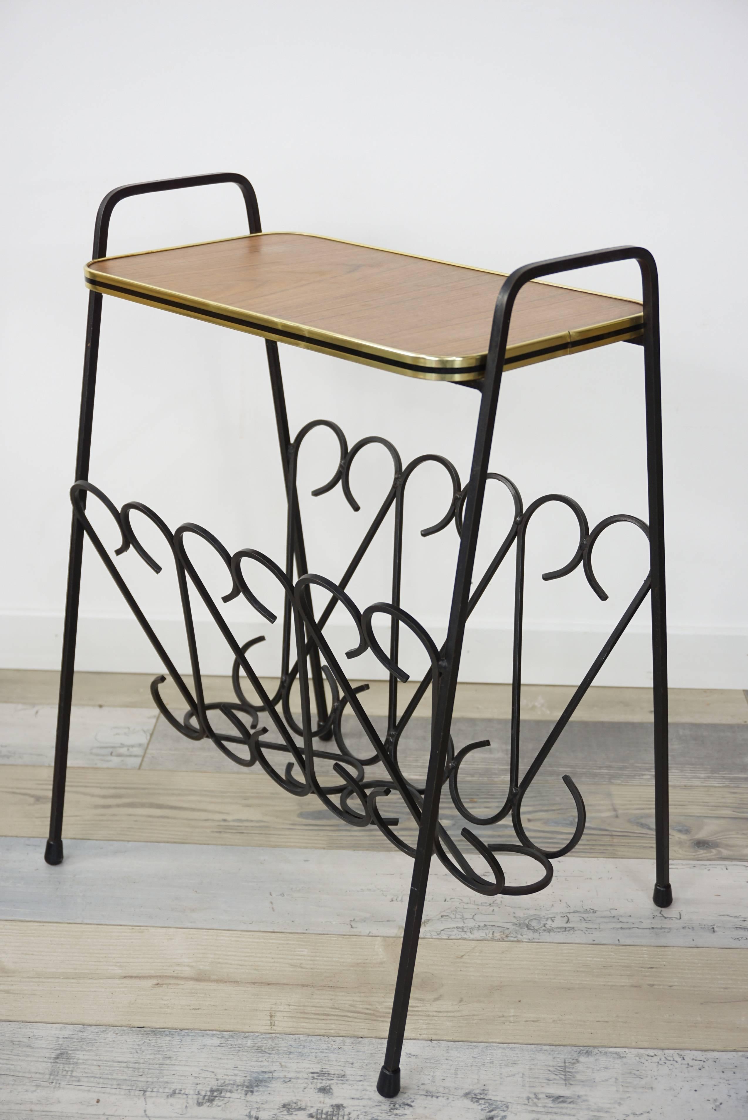 1950s design side table composed of a wrought iron structure forming a magazine rack and a wooden shelf.