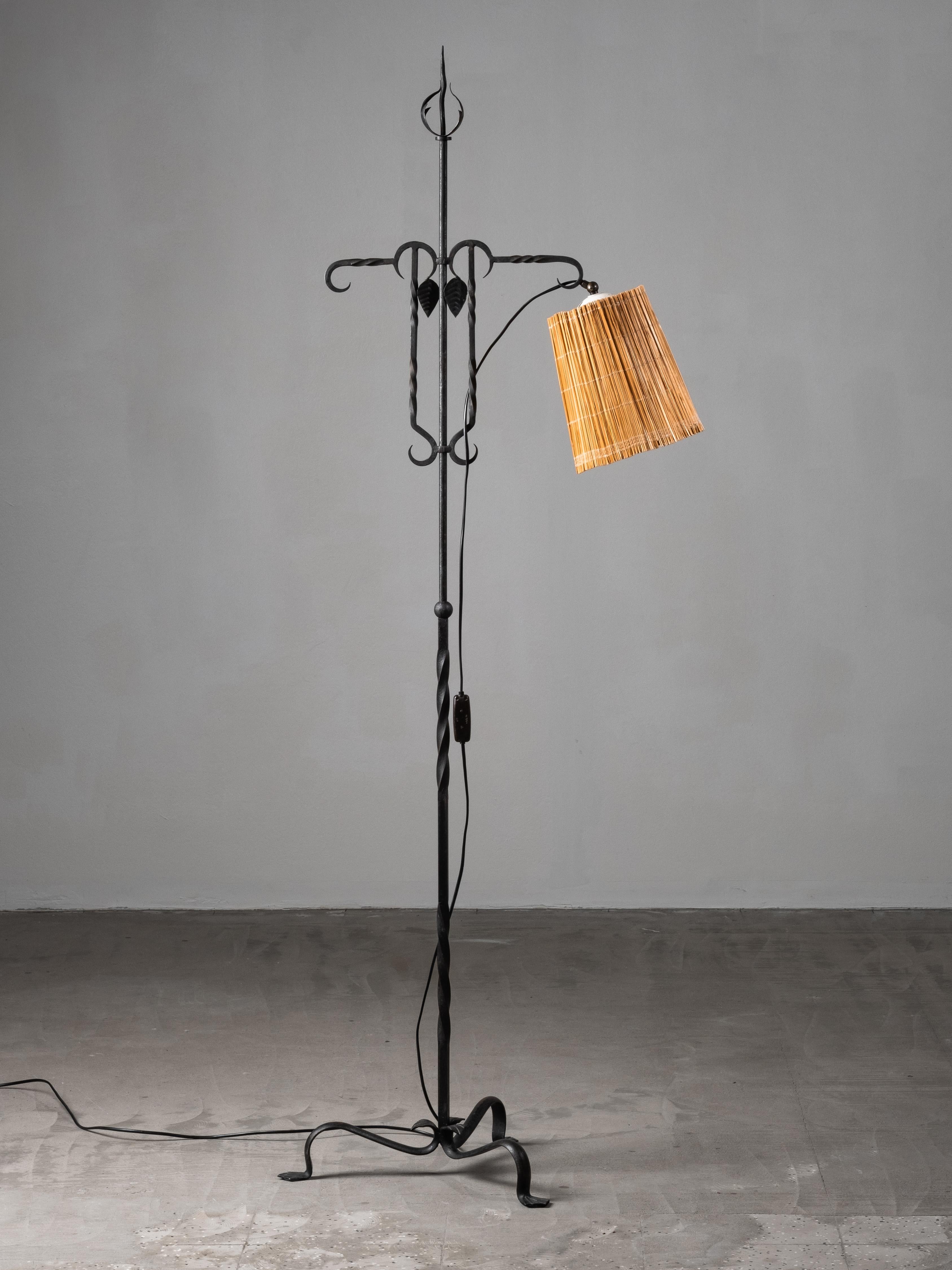 Expresiva lámpara de pie forjada a mano por Taidetakomo Hakkarainen, Finlandia, fabricada en la década de 1930. El escultural armazón de hierro forjado, coronado con un remate en forma de llama y adornado con detalles de hojas cortadas a mano,