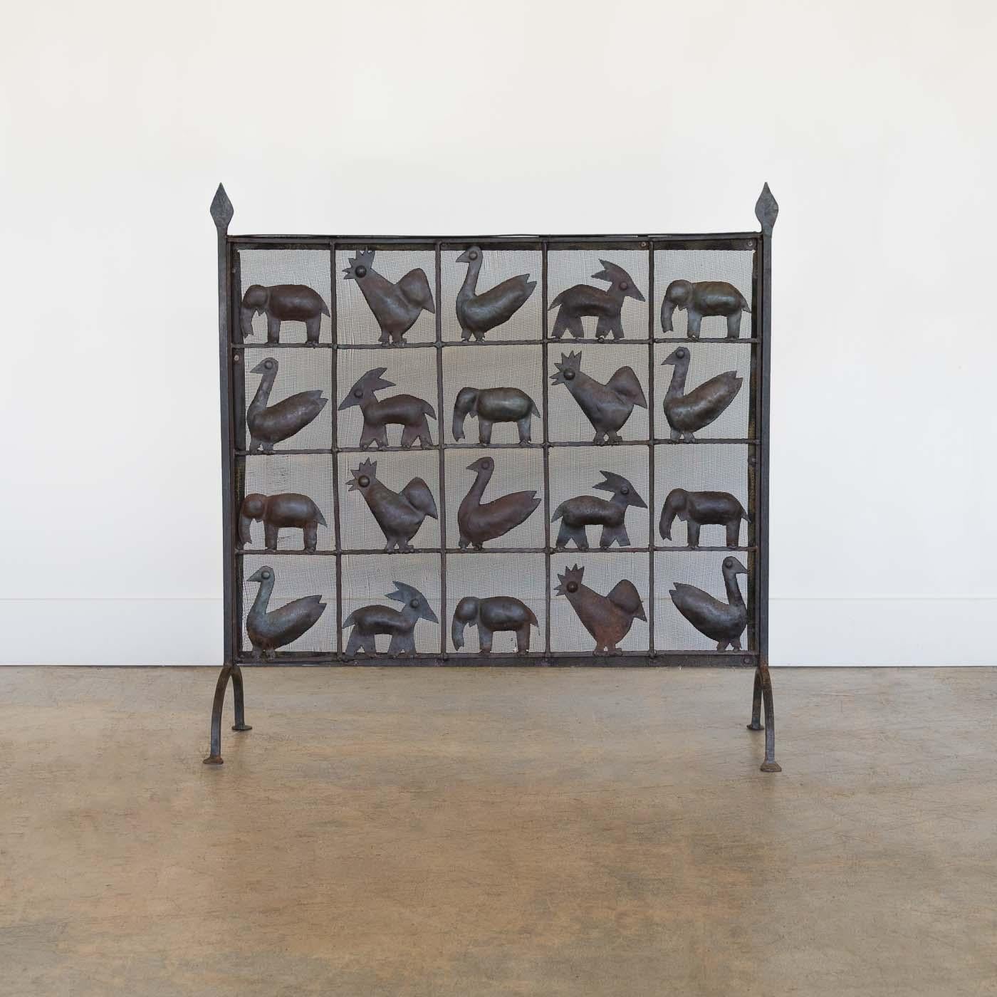 Incredible wrought iron animal fire screen by Atelier Marolles, France, 1955. Unique decorative piece showcasing a grid of little roosters, geese, goats, and elephants with dense mesh background. Hand forged iron details and arched iron legs at