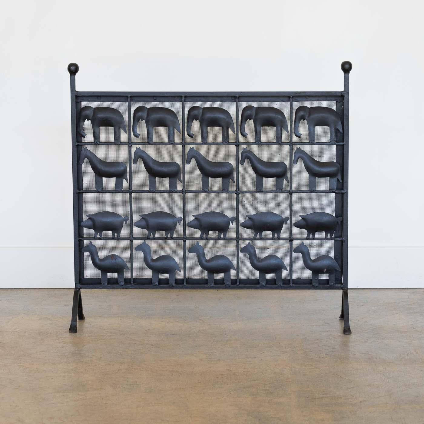 Incredible wrought iron animal fire screen in the style of Atelier Marolles, France, 1955. Unique decorative piece showcasing a grid of little horse, pigs, llamas, and elephants with dense mesh background. Ball iron details on top and arched iron