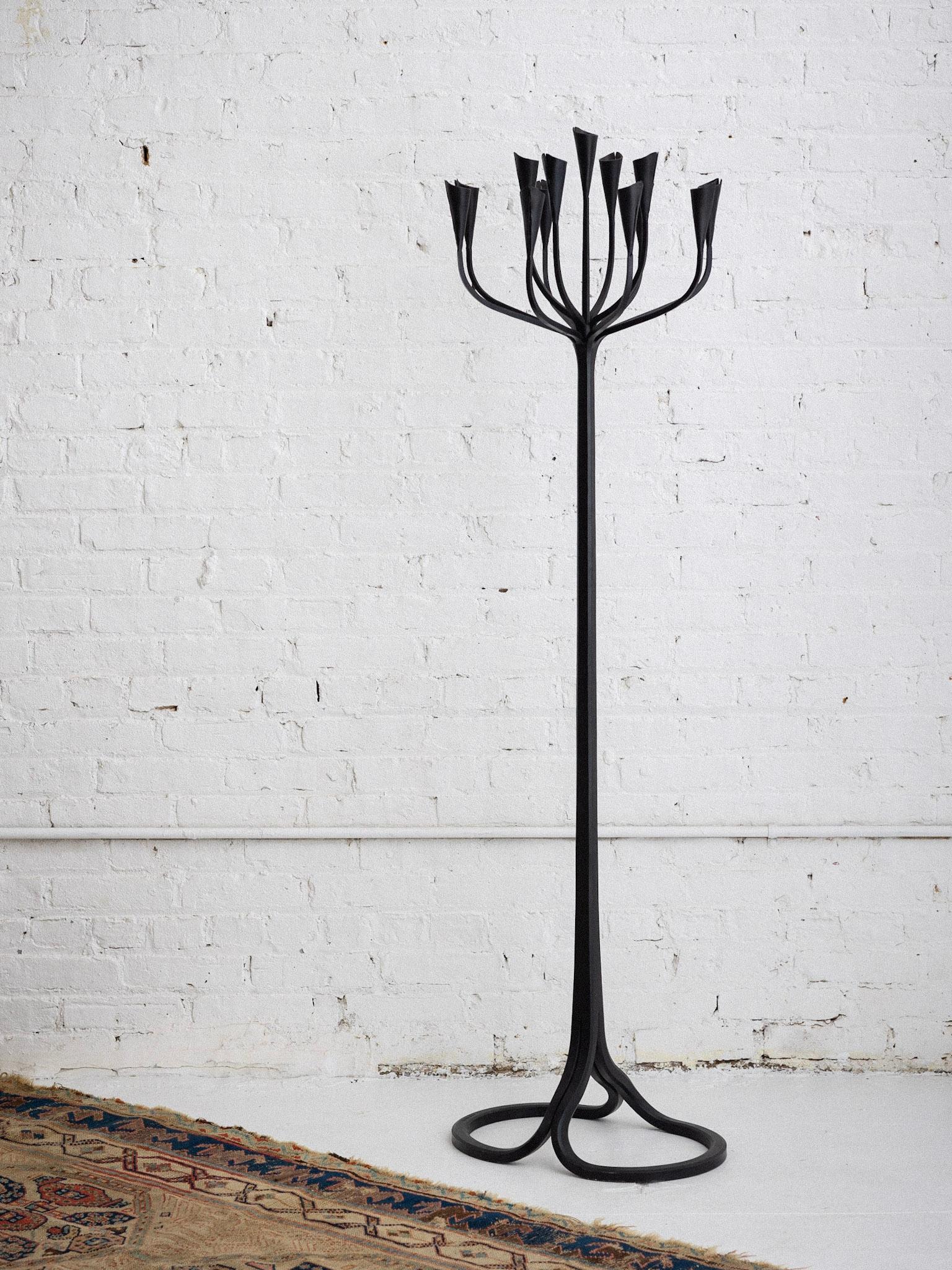 A hand crafted wrought iron candelabra by artist Gregory Litsios. Heavy iron base supports 13 candle inserts for various size tapers. Signed “Gregory Litsios.”