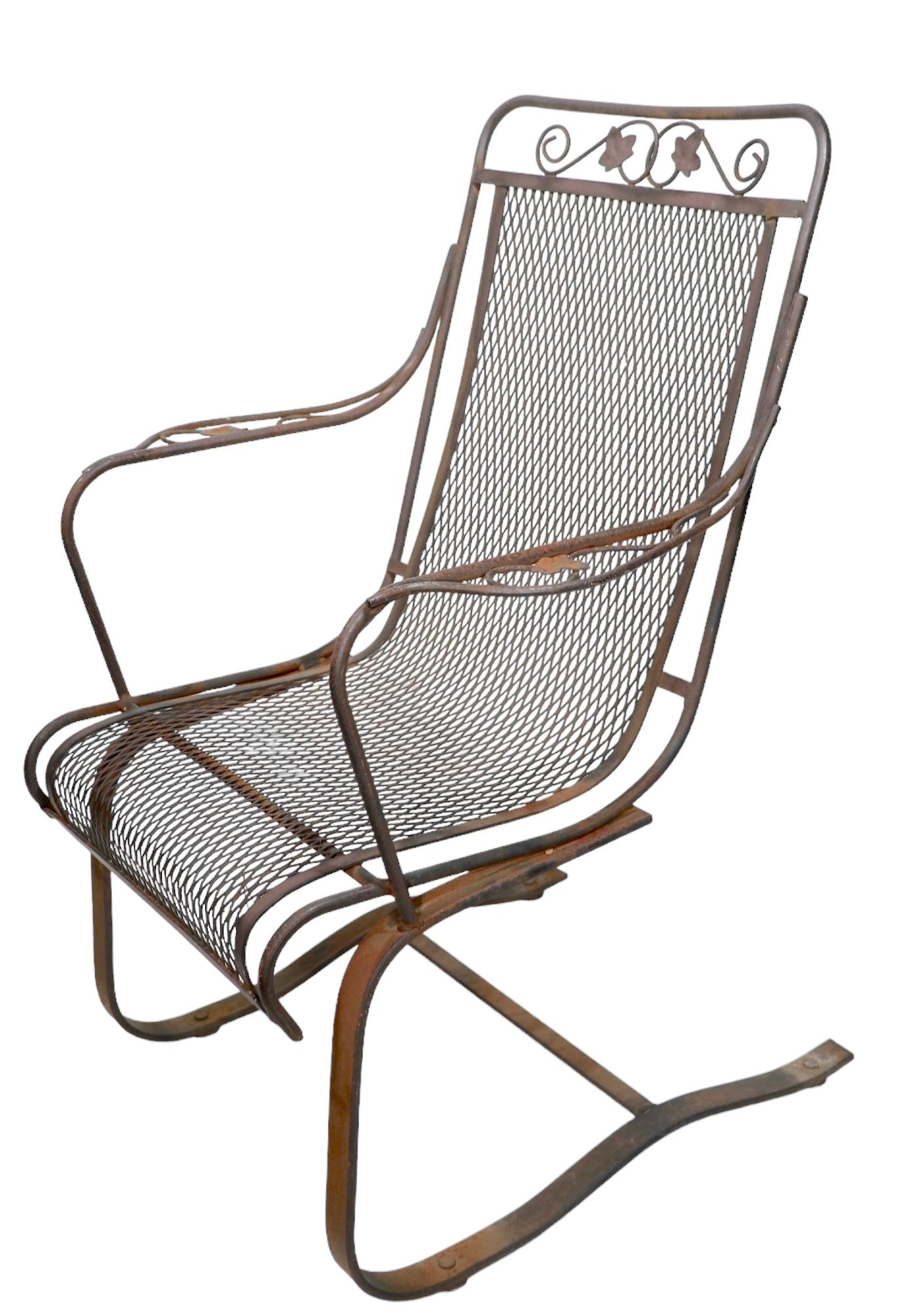 Classic vintage garden, patio, poolside high back lounge, arm chair, attributed to Salterini, or possibly Woodard. The chair features a wrought iron frame, with a continuous metal mesh seat and back rest, on a cantilevered spring base. The chair is