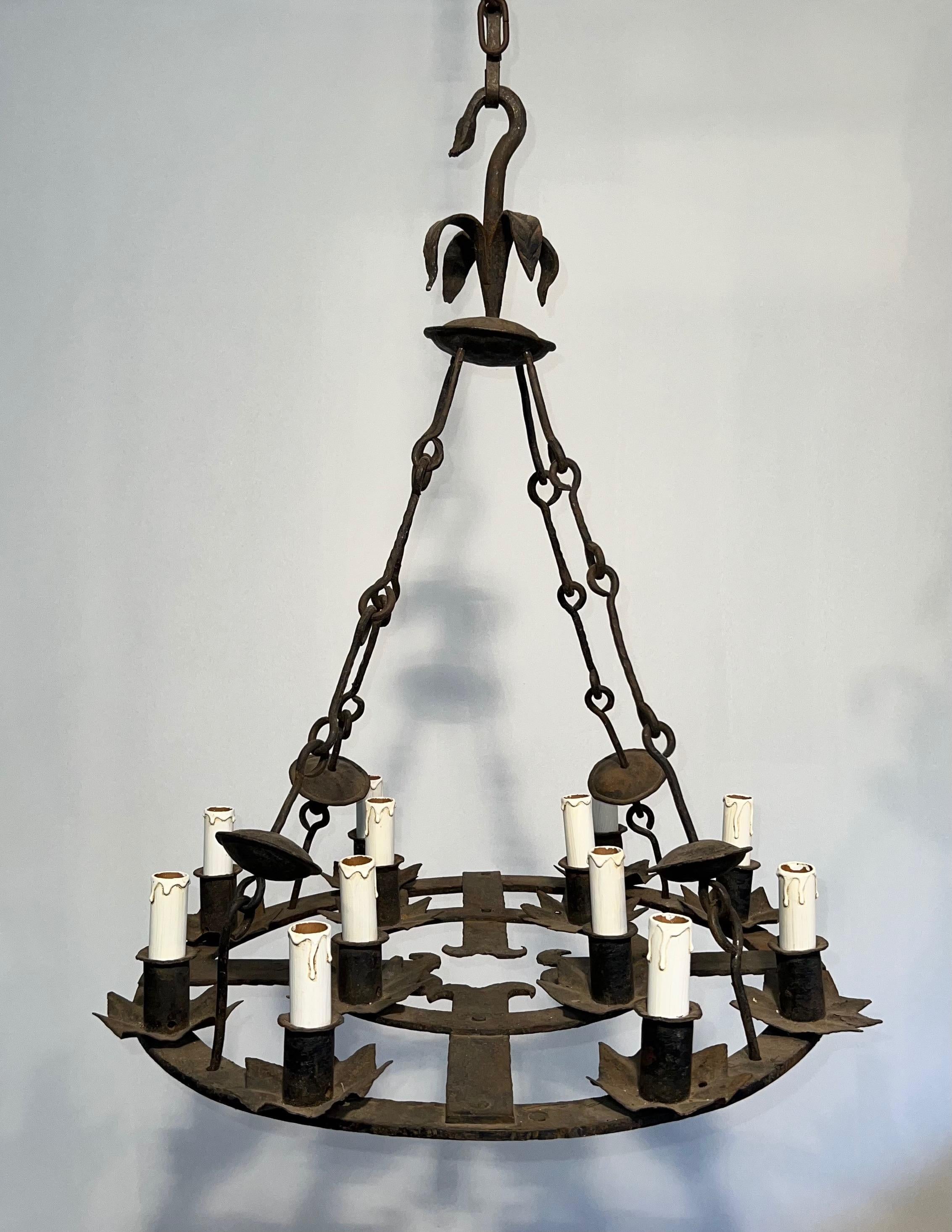 Questo bellissimo lampadario a 12 luci è realizzato in ferro battuto. Si tratta di un'opera francese in stile gotico. Circa 1950