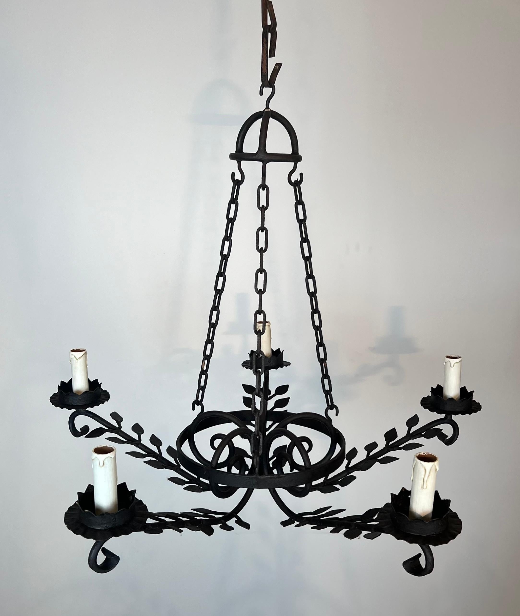 Questo simpatico e decorativo lampadario a 5 bracci è realizzato in ferro battuto. Il lampadario è decorato con foglie sui bracci. Questa è un'opera francese. Circa 1950