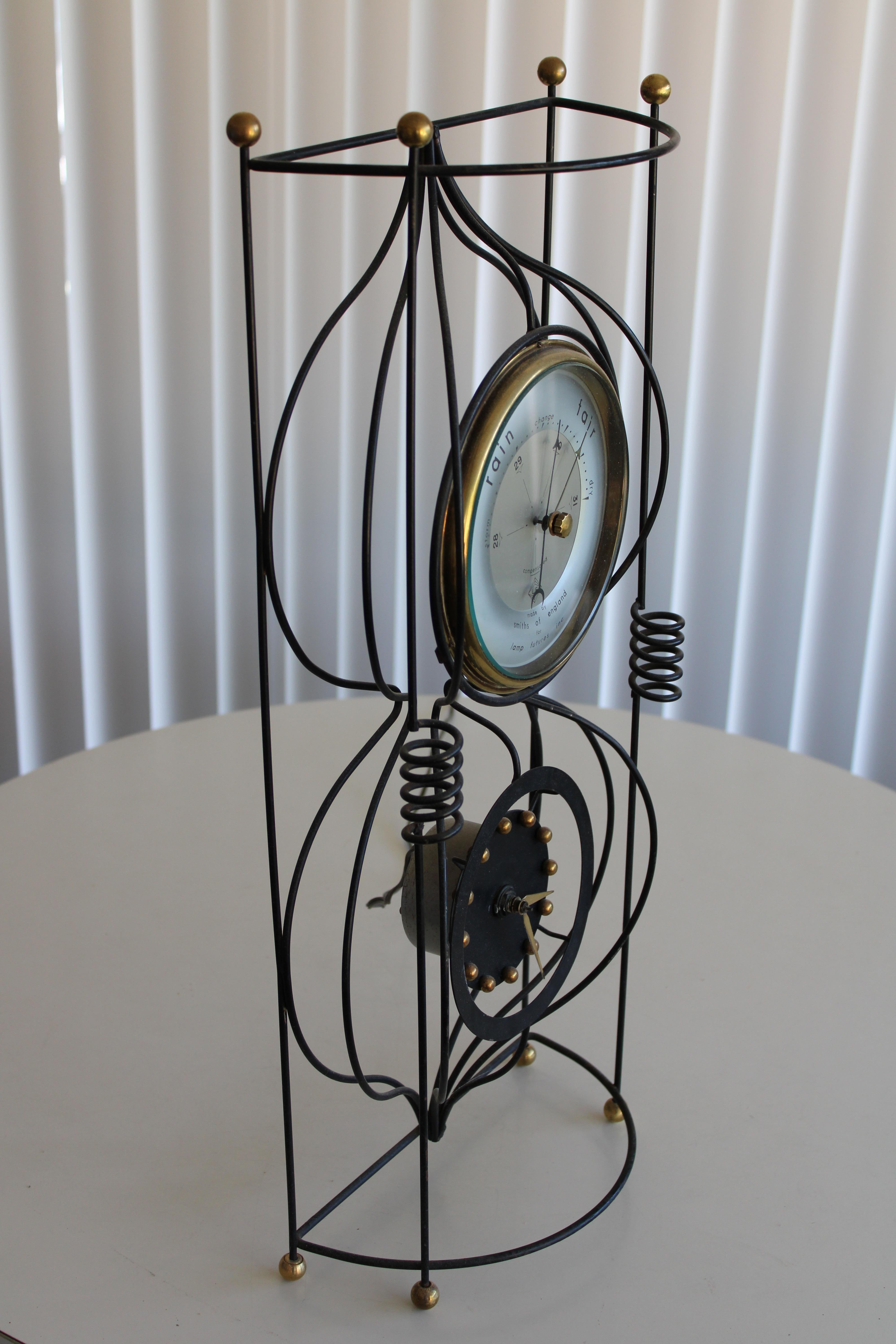 A mid-century atomic style clock barometer combo. Black wrought iron frame with solid brass spheres top and bottom and marking the hours. Barometer is marked Smiths of England for Lamp Futures Inc. Electric clock keeps perfect time and runs quietly.