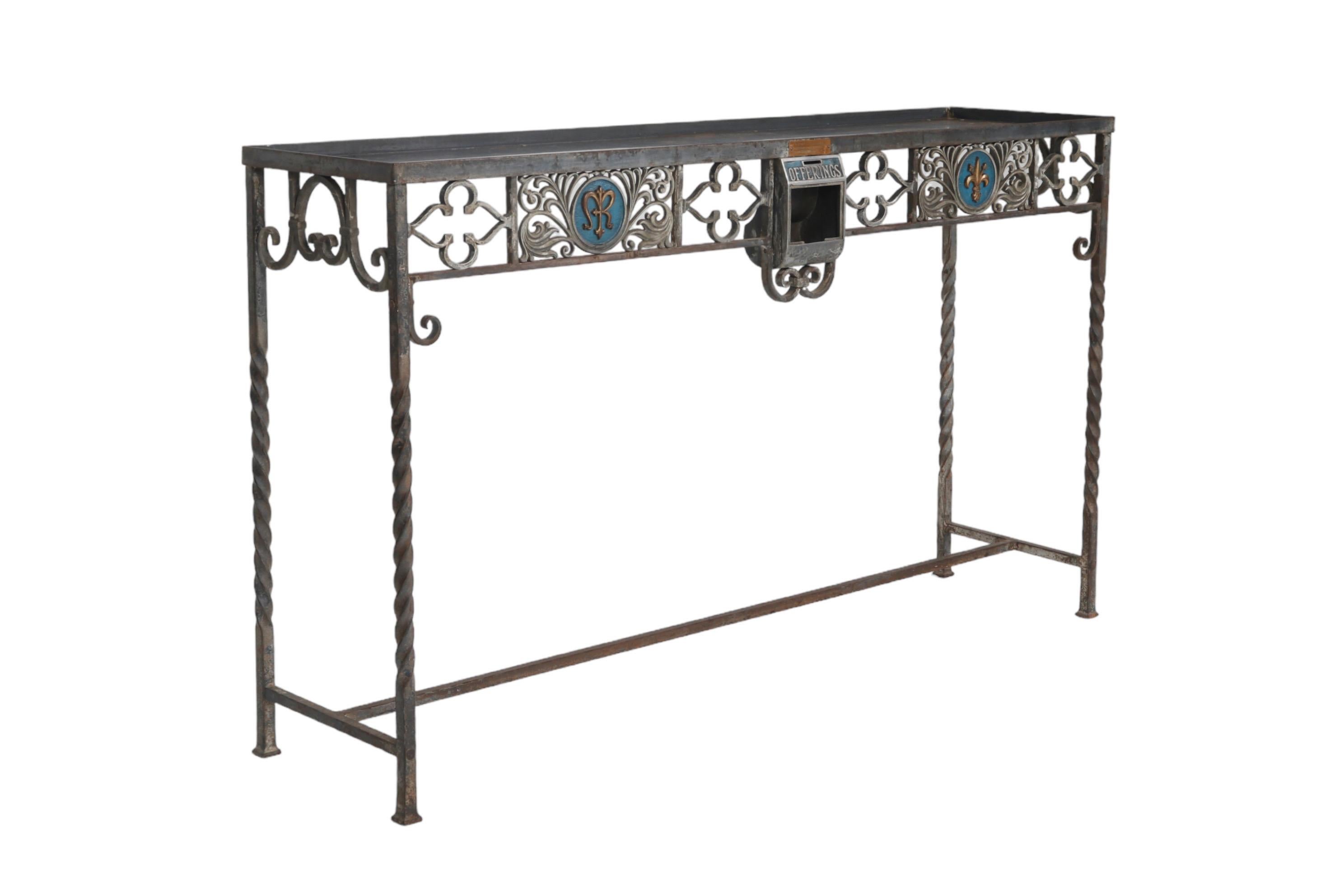 A custom made wrought iron console table with a tray-like top. An ornate skirt in front and at each side is decorated with loose flower shapes in wrought iron. Two pierced plates of acanthus scrolls have medallions in blue, pressed with a gilt fleur