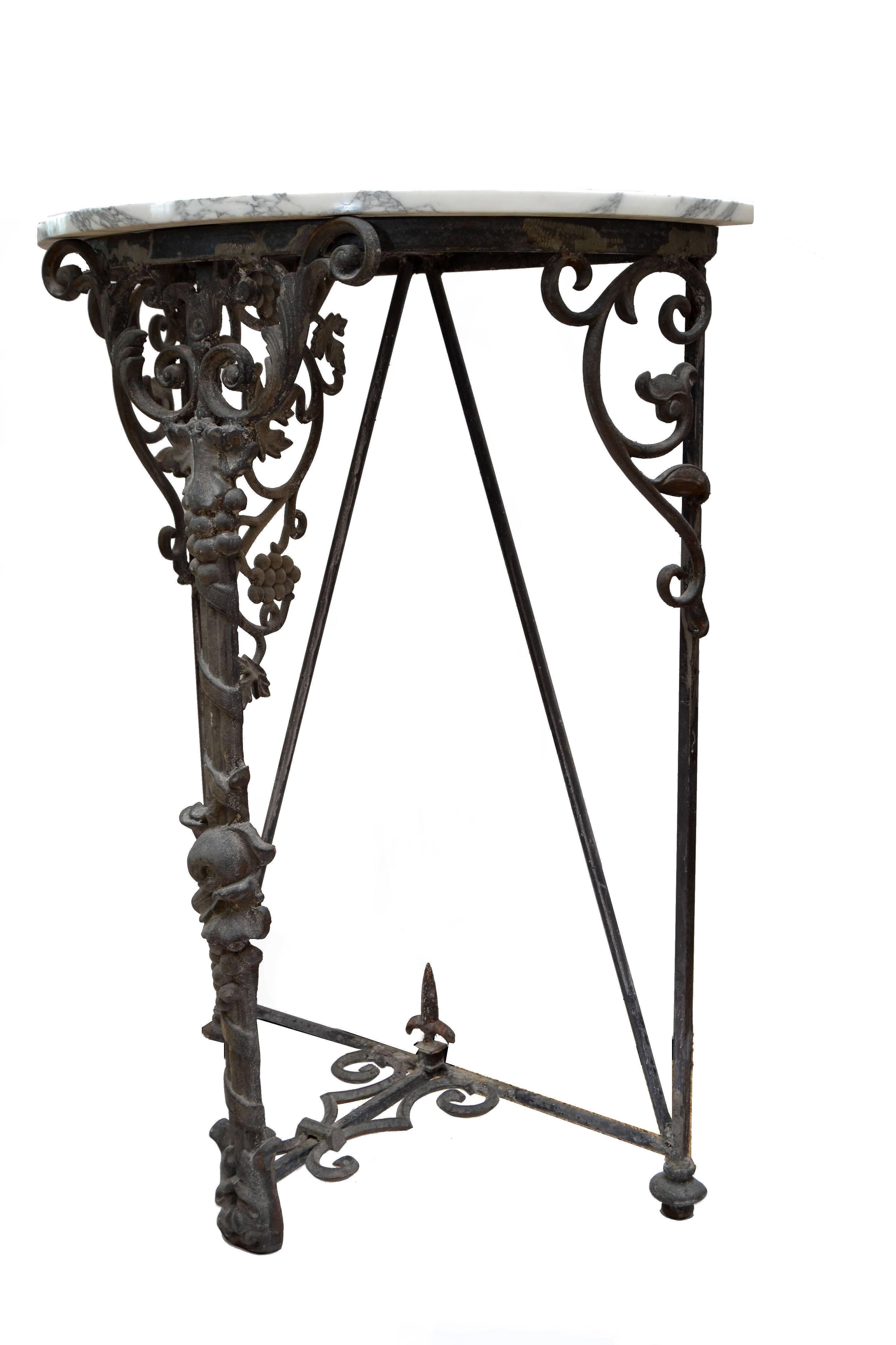 Wrought iron demilune console with marble top.
Featuring grapevines at center front. Perfect for a wine cellar or small patio.
 