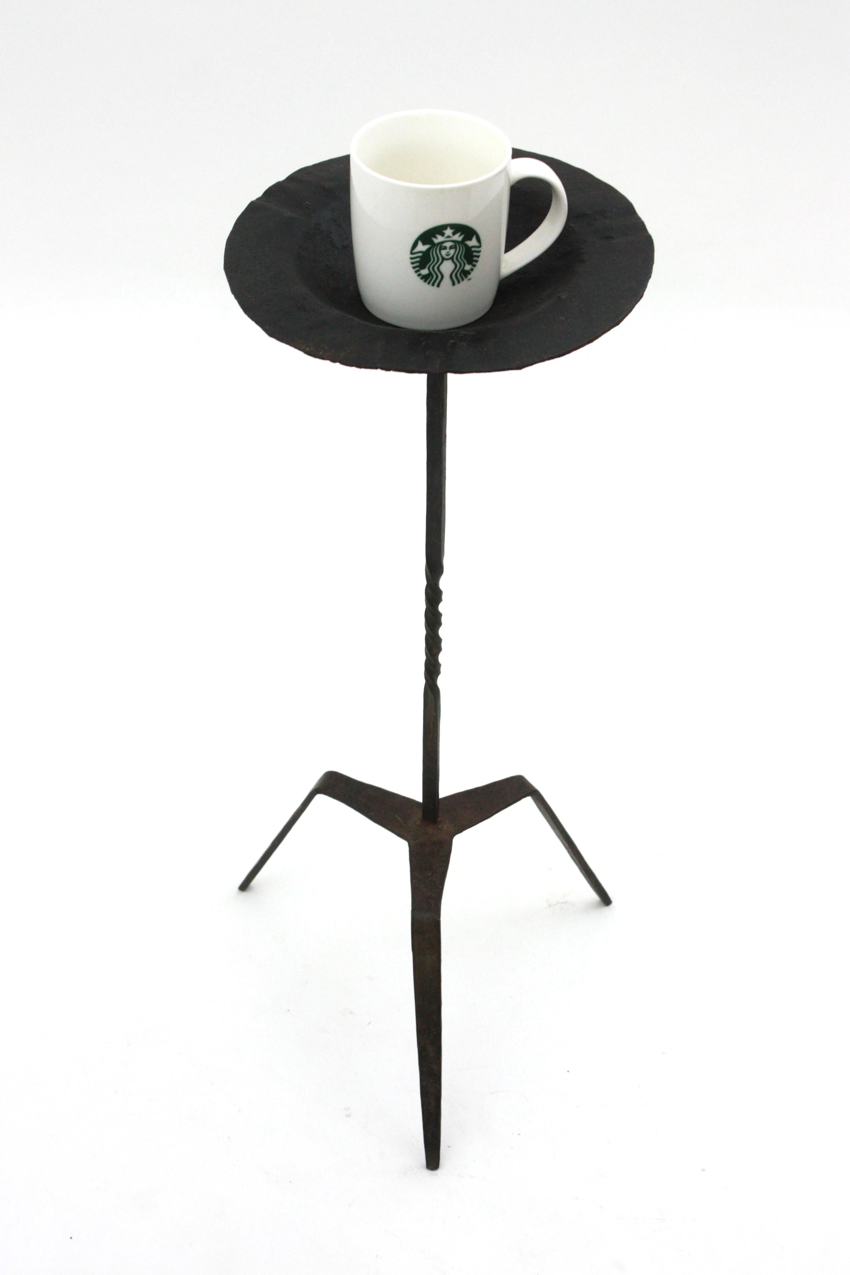 Spanish wrought iron floor ashtray or drinks / cocktails table standing on a tripod base, Spain, 1940s.
Handcrafted in wrought iron. The top stands on a tripod base with twisting details on the stem and scroll endeded feet. Terrific parcel-gilt