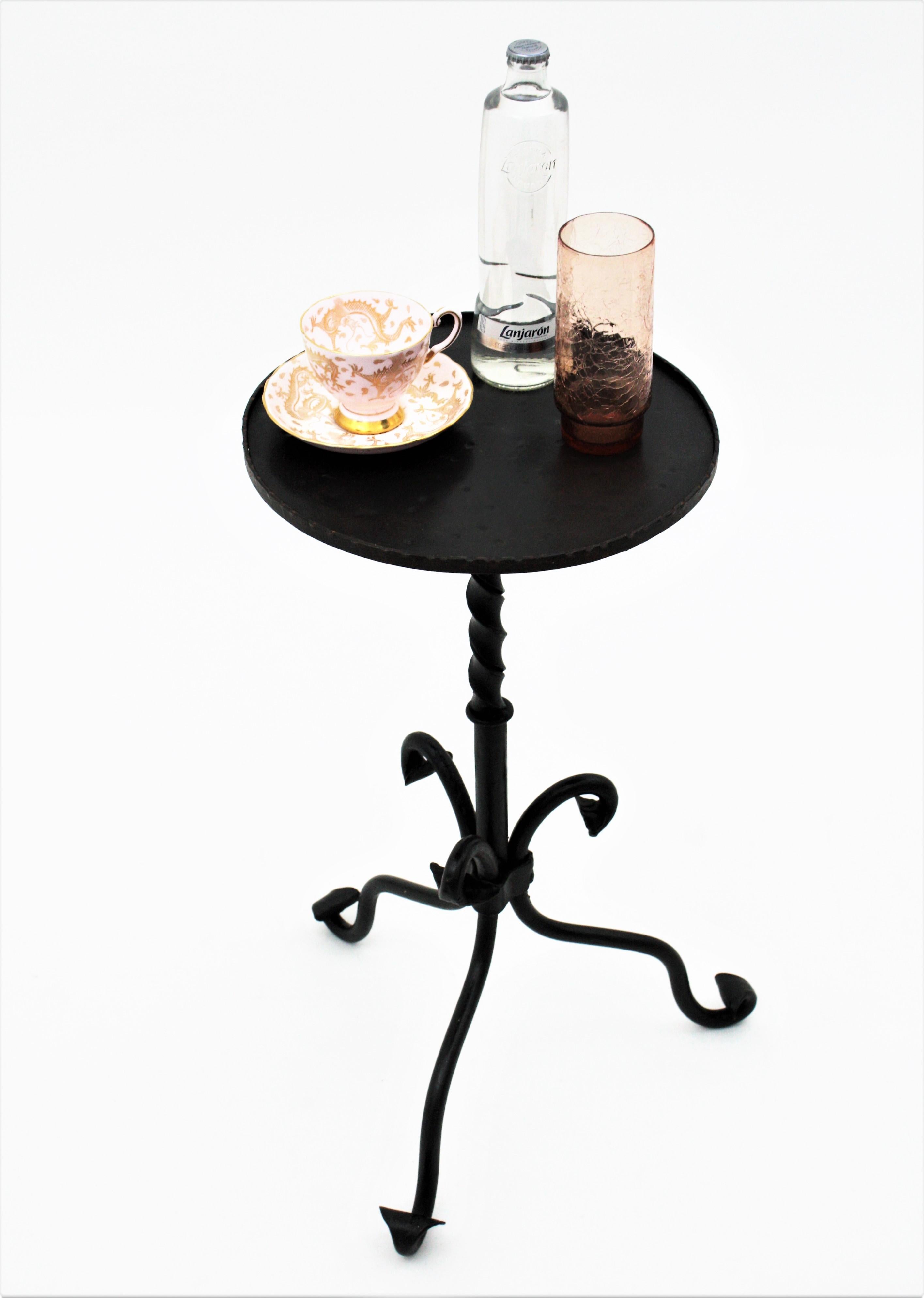 Elegant Gothic style hand-hammered iron round gueridon table standing on a tripod base. Spain, 1940s.
This wrought iron black painted table has twisted details at the steam and the top stands on a tripod base with scroll endings at each leg.
This