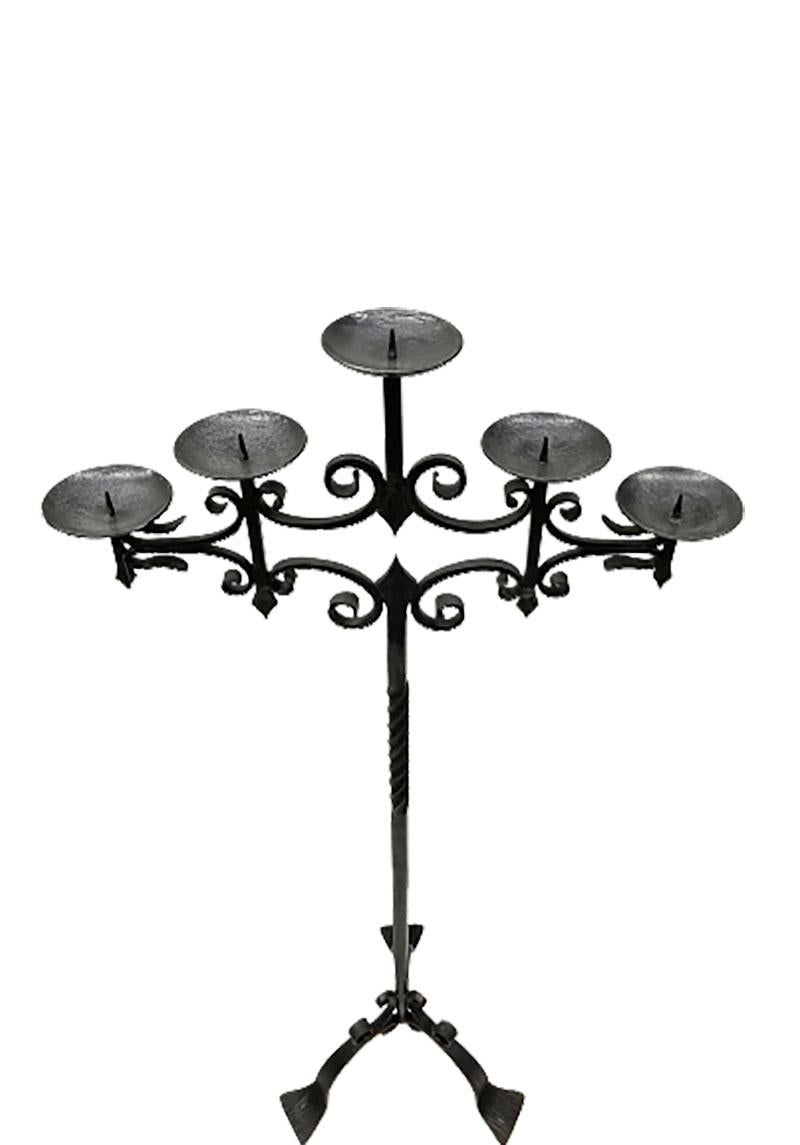 Wrought iron floor candleholder

A wrought iron standing tripod floor candleholder with 5 candle holders with collars on a partially turned Stand. 
The collars of the candle holders are 11.3 cm diagonal.
Age is around 1960s / 1970s
In total is