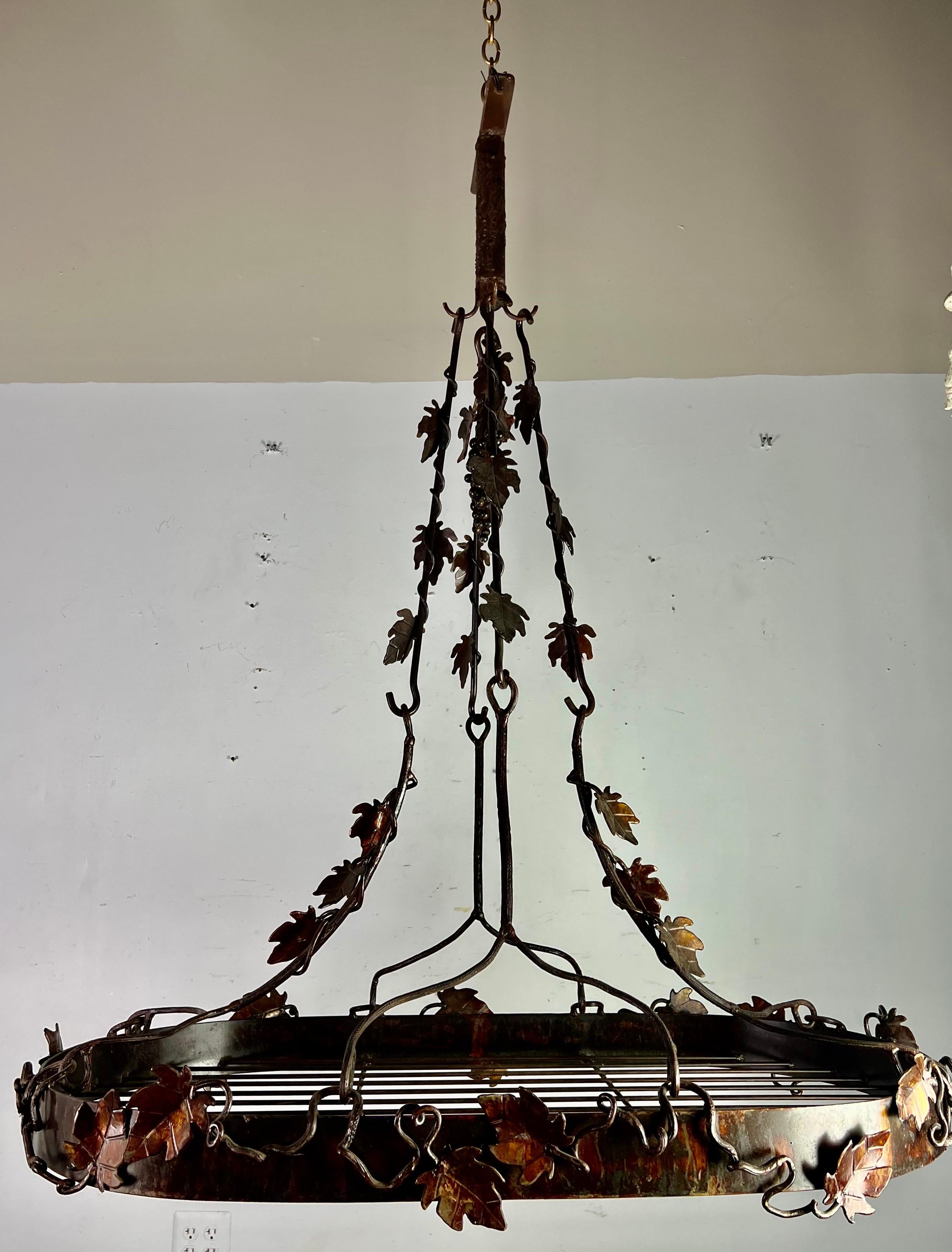 20th Century hand forged wrought iron pot rack with decorative vines and leaves throughout. It was hand made out of iron and finished with a hint of copper color to give a radiant glow and coordinate with your copper pots.