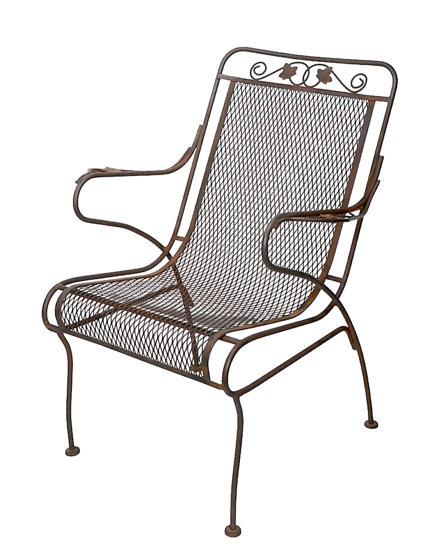 Classic vintage garden, patio, poolside high back arm, or lounge chair, in very good, original condition. 
The chair features a wrought iron frame with a continuous metal mesh seat and back rest. Attributed to Salterini, or possibly Woodard, circa