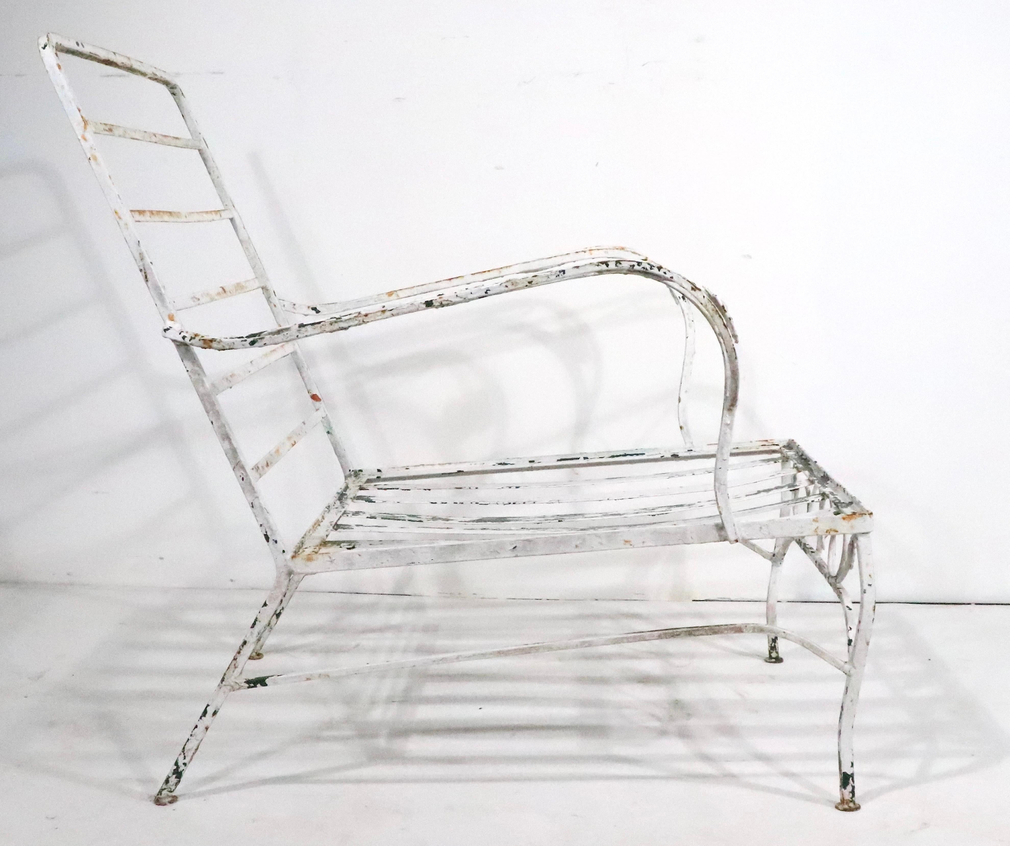 Stylish low wrought iron garden, patio, poolside  lounge chair attributed to Salterini, in the style of Woodard. The chair is structurally sound and sturdy, the old paint finish, shows considerable wear, please see images. 
Usable as is or we offer