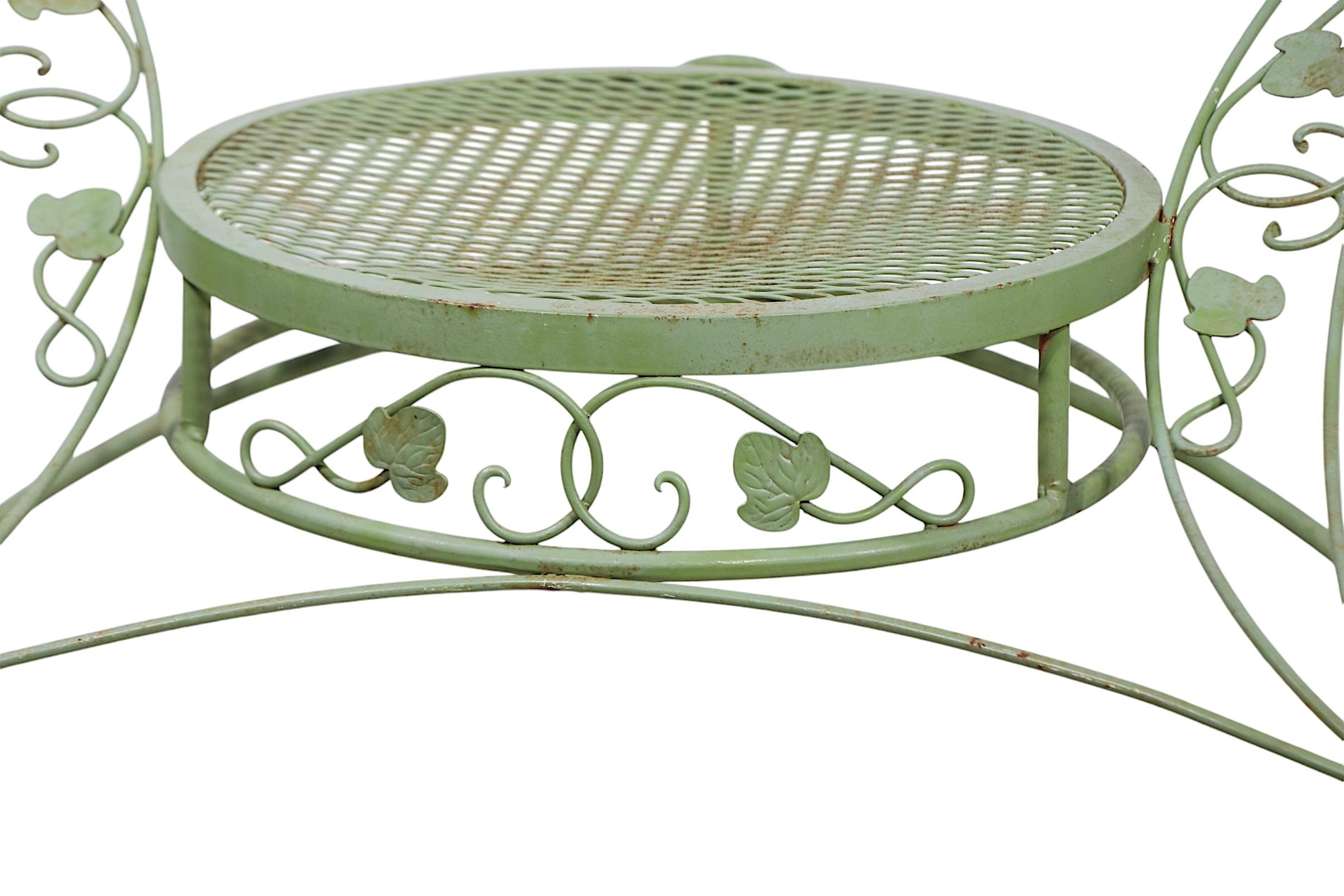 Chic vintage  wrought iron Tete a Tete by the  Woodard Furniture Company circa 1950/70's. This piece features two Sculptura round chairs joined into one piece  by a small side / drinks  table.  This example is in very good, clean, ready to use