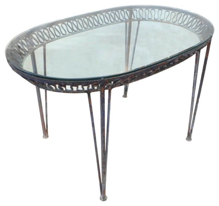 A wonderful wrought iron and glass console table by Salterini. A racetrack-shaped top with tapering triple-stem legs and a ruffled, Royere-like apron. Heavily and beautifully well constructed. Wears an appealing, mottled and oxidized surface