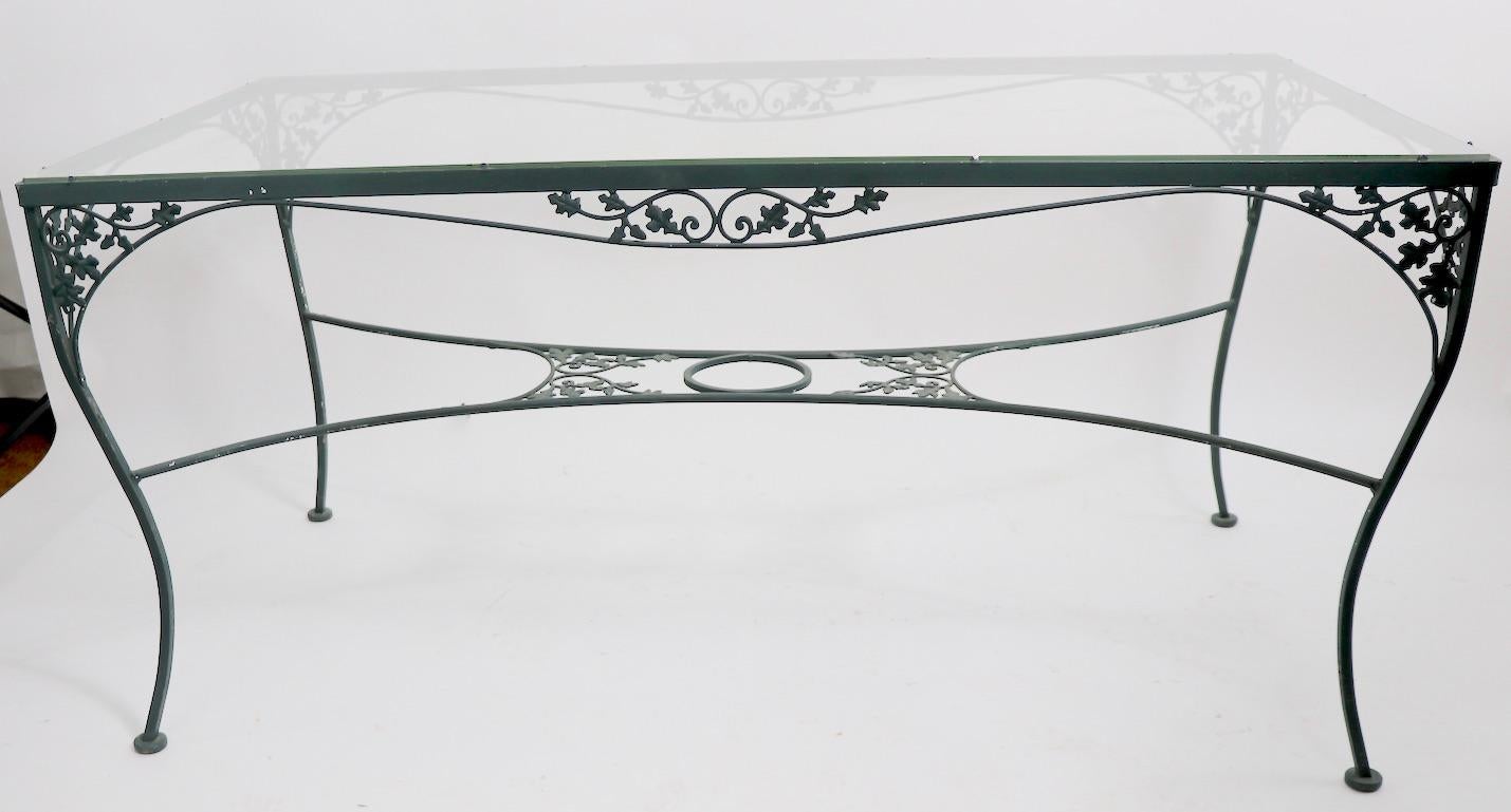 Wrought, cast iron and glass top patio, garden, sunroom dining table by Woodard. Unusual large scale table in clean original condition. (top has inconsequential chip at one edge, please see images.)
  