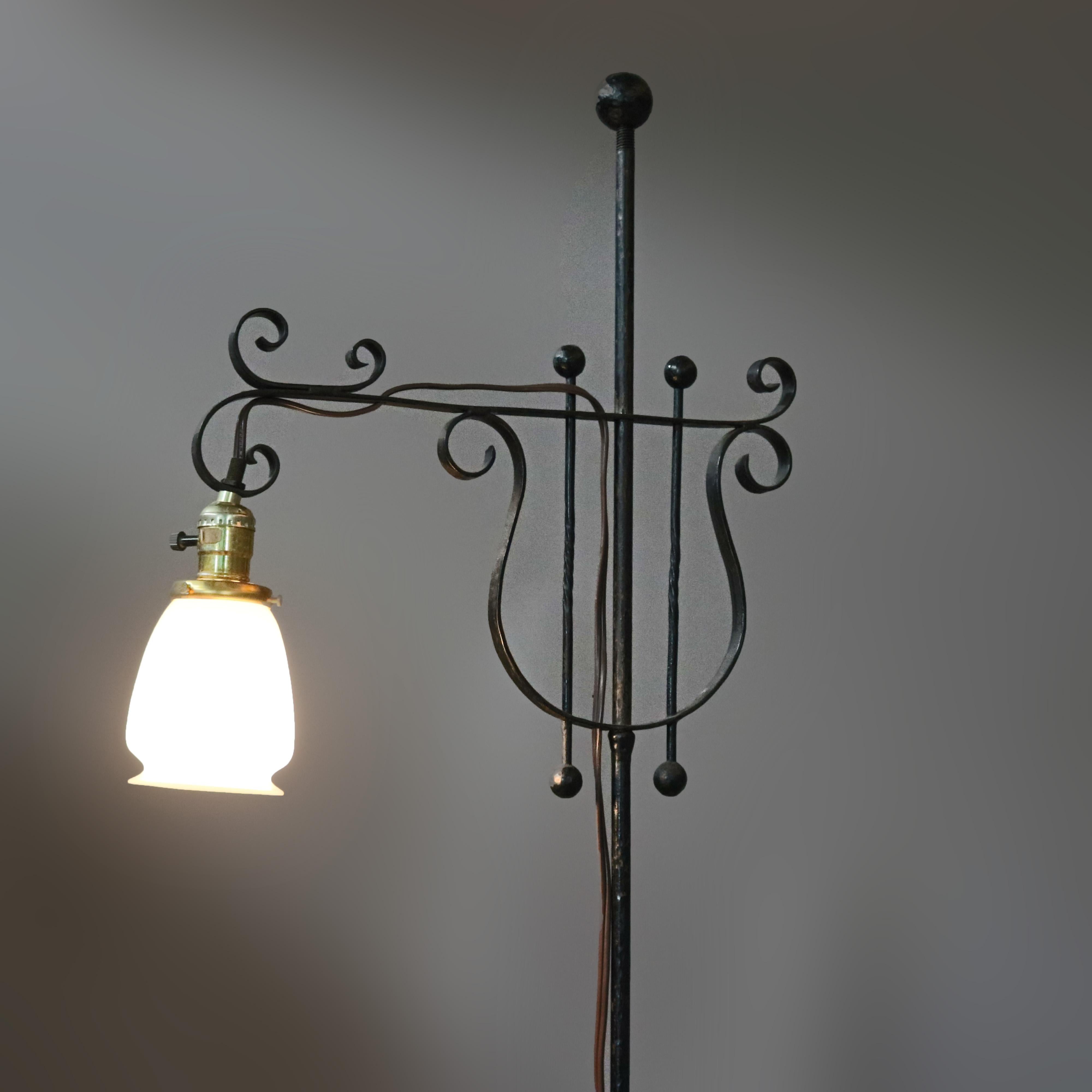 An antique gooseneck floor lamp offers wrought iron construction with lyre form frame with scroll elements throughout, art glass shade, circa 1920.

Measures: 66.5