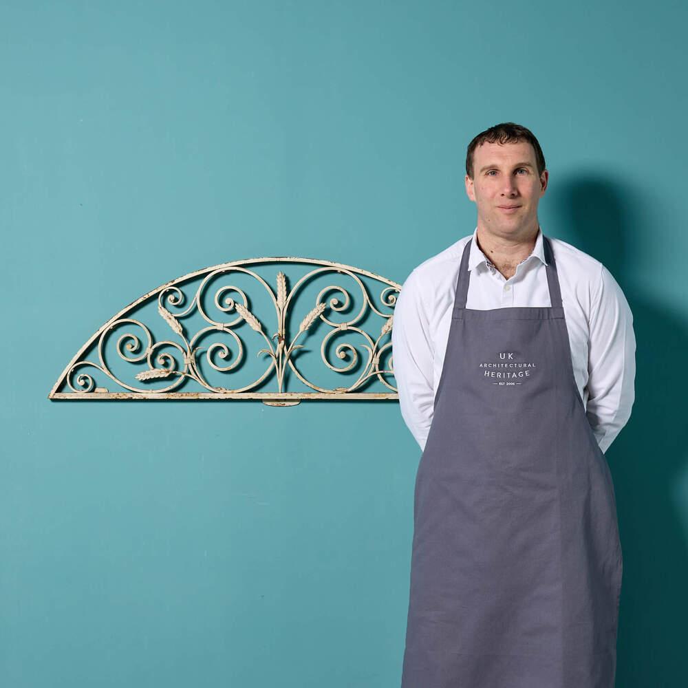 A reclaimed wrought iron painted fanlight salvaged from the Crescent in Bath. Constructed in wrought iron with a rustic painted finish, this elegant panel features repeating scrolls and wheat sheafs to its centre. Perfect for use as a decorative