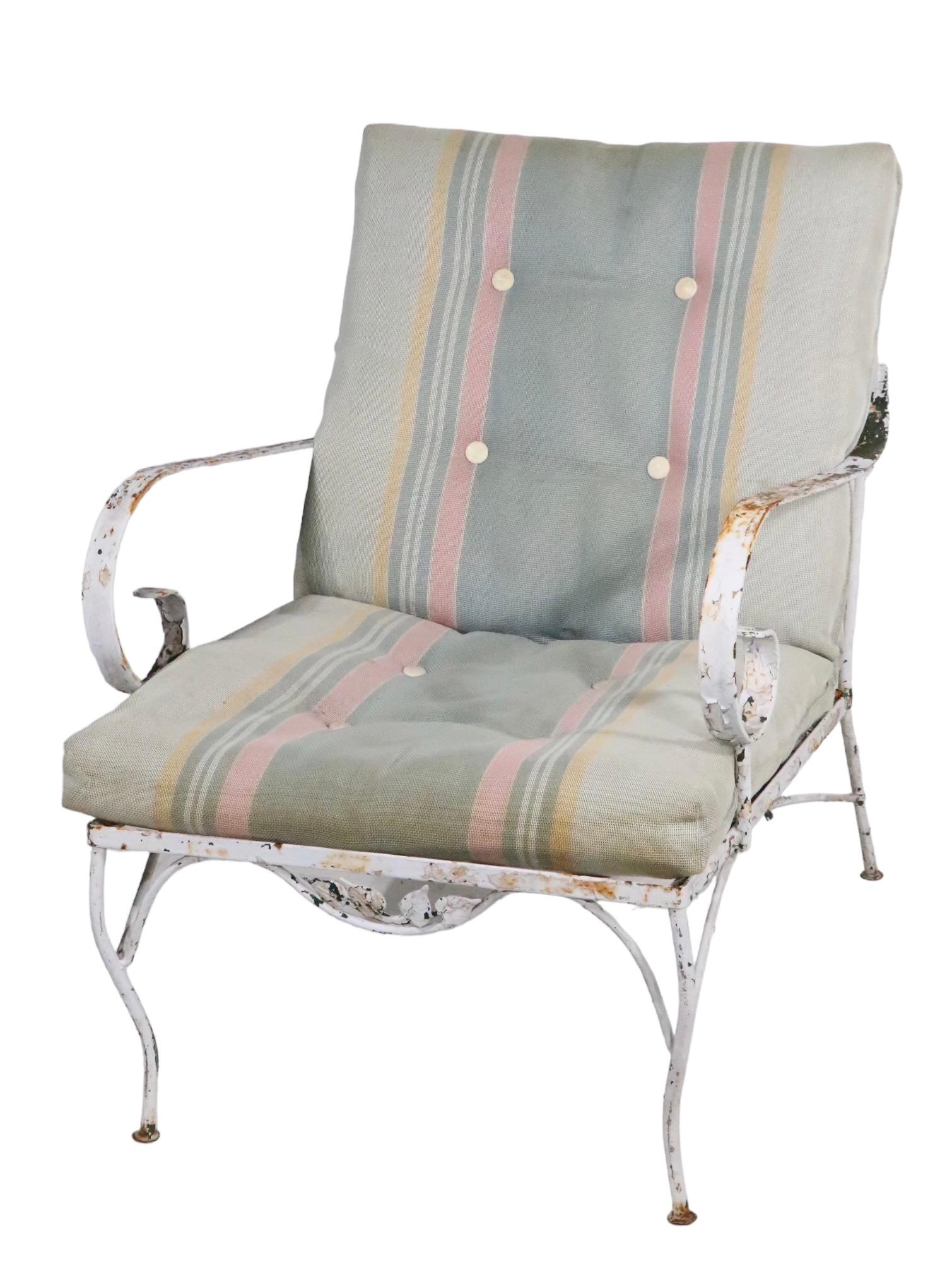 Chic wrought iron lounge chair, having a dramatic exaggerated scrolled arm rest and decorative metal foliate trim. The chair is structurally sound and sturdy, the paint finish shows considerable wear, please see images. Usable as is or we also offer