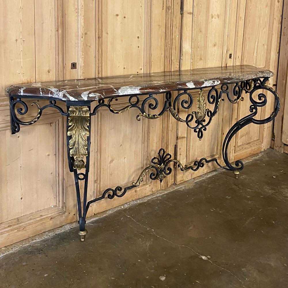 Wrought iron marble top console, French Louis XIV style, 19th century represents the grandeur of the style, with an elegantly scrolled hand forged wrought iron base enhanced by acanthus plumes highlighted in gold. The boldly styled legs are set at