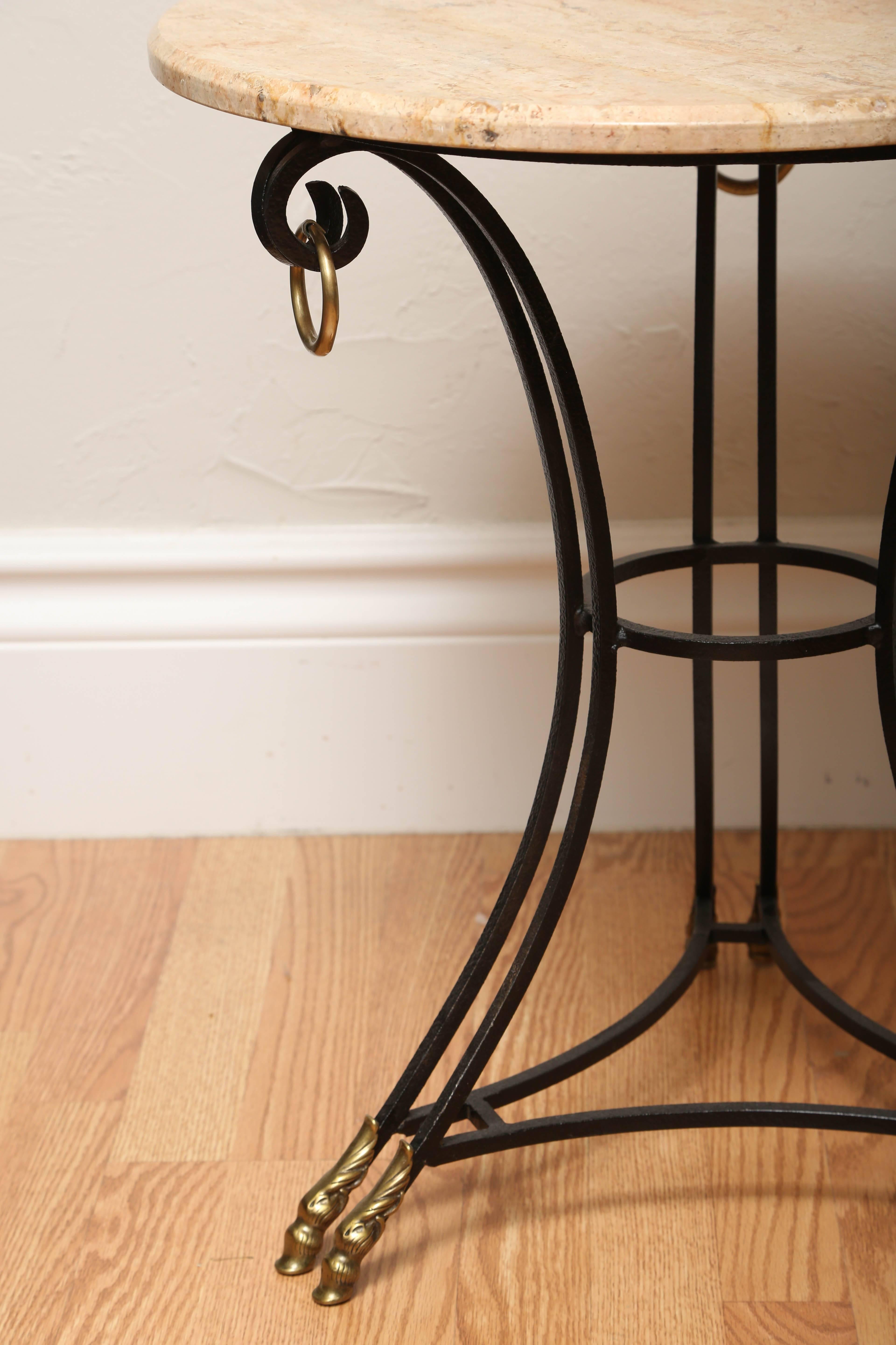 Wrought iron and brass trimmed gueridon with three heavy brass rings and six brass hoofed feet. Italian marble top.