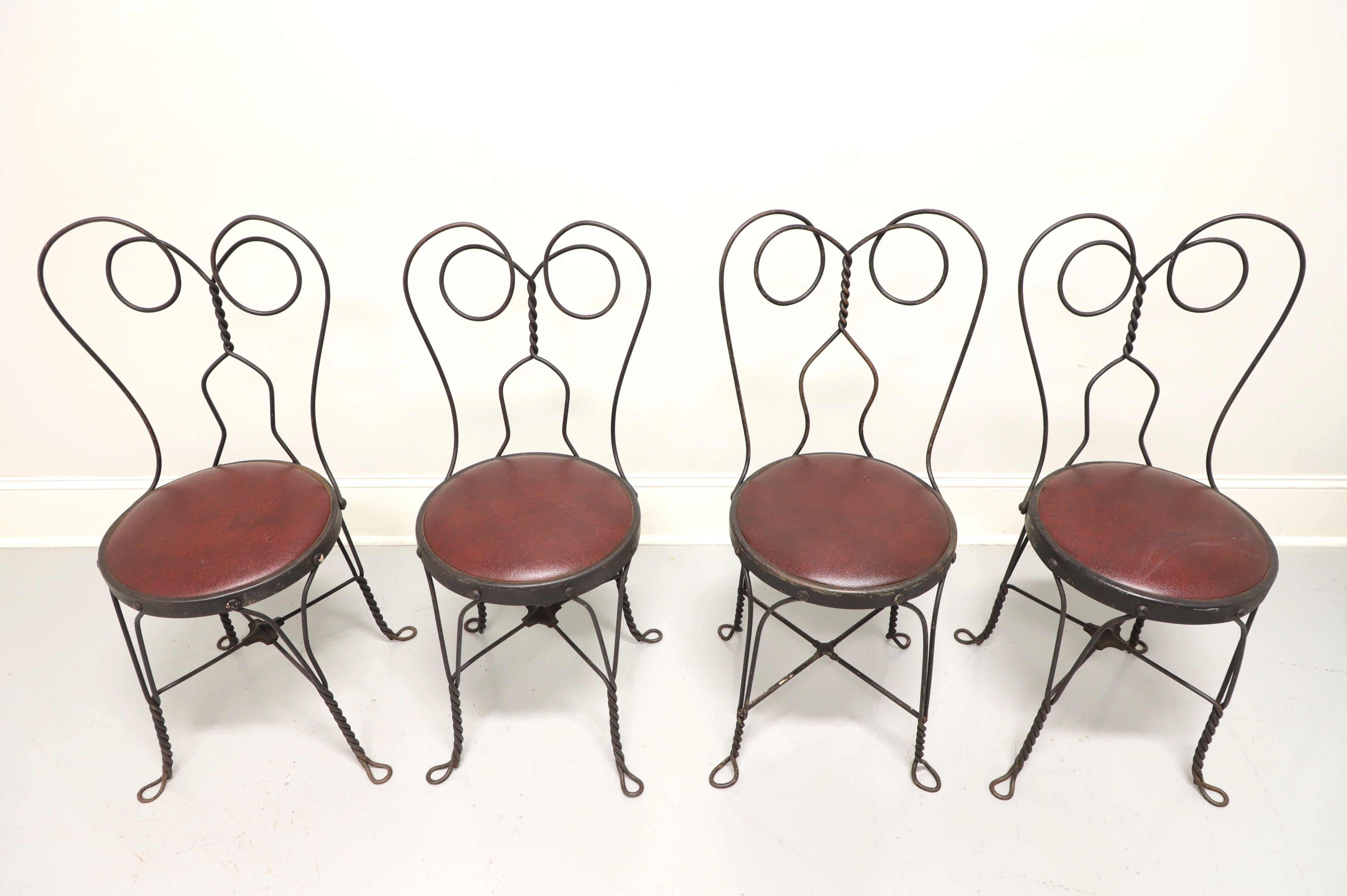A set of four Victorian style wrought iron ice cream parlor bistro chairs, unbranded. Wrought iron metal frames, distressed black painted finish, burgundy color upholstered seats, twisted backs and legs. Ready for a fresh coat of paint or can be