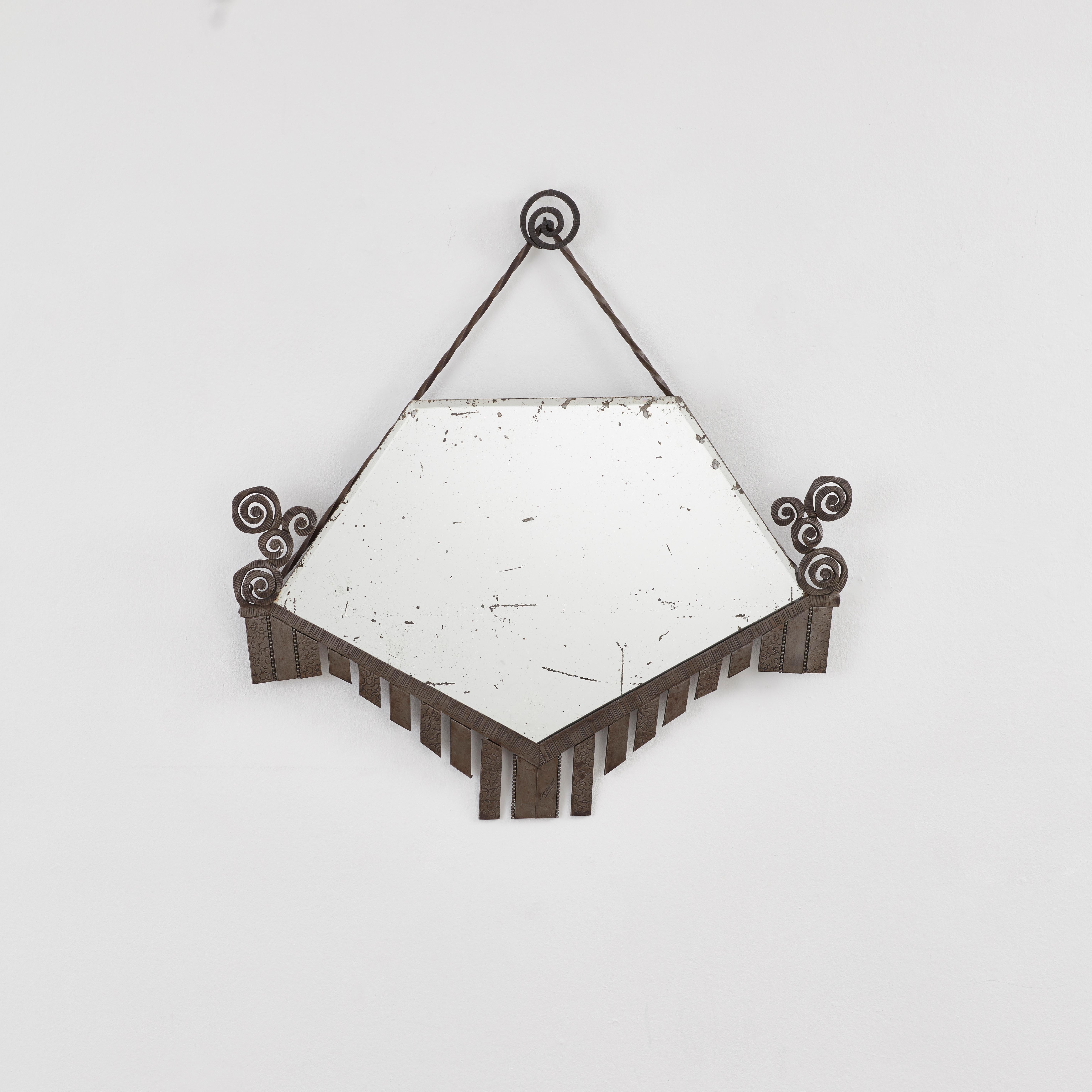 A mirror that holds the mark of the forge. This French fer forgé bevelled mirror features a geometric frame, flanked by spiralling, rosette-like flourishes. The manual craft of ironwork is tactile and evident — see the stamped circles, linear