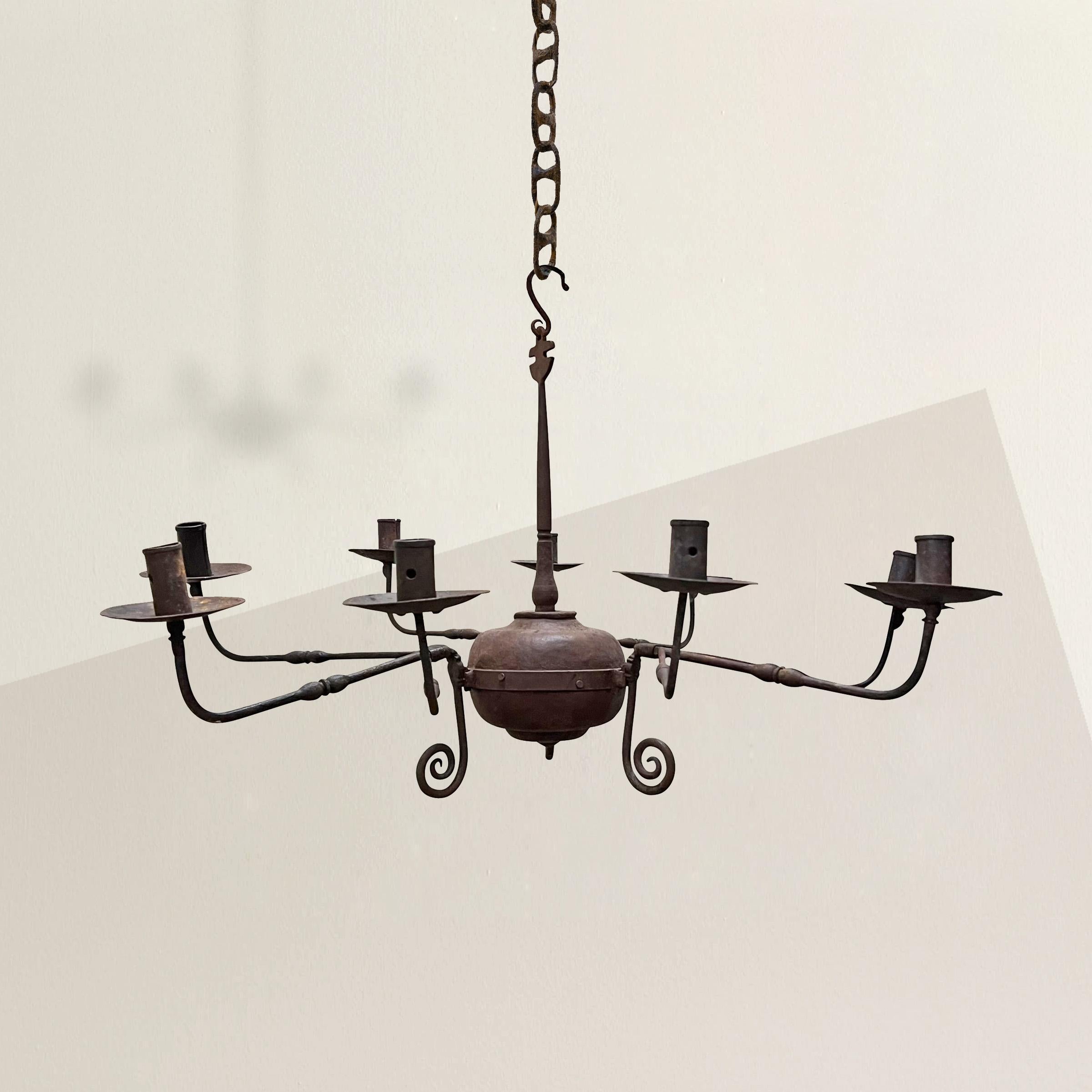 A whimsical and charming 20th century handwrought-iron nine-arm chandelier with a large central sphere with three arms radiating out from the center, each with three arms supporting nine candle cups. This piece would blend seamlessly into any modern